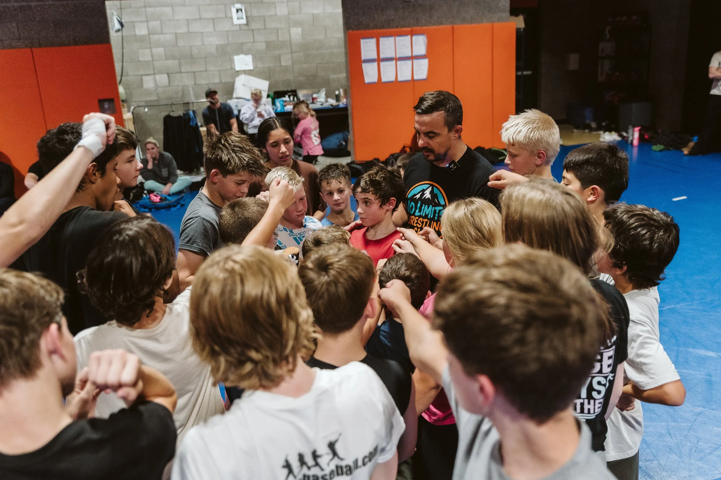 Youth wrestling coach talking with an athlete between matches, reinforcing mindset, accountability, and emotional resilience.