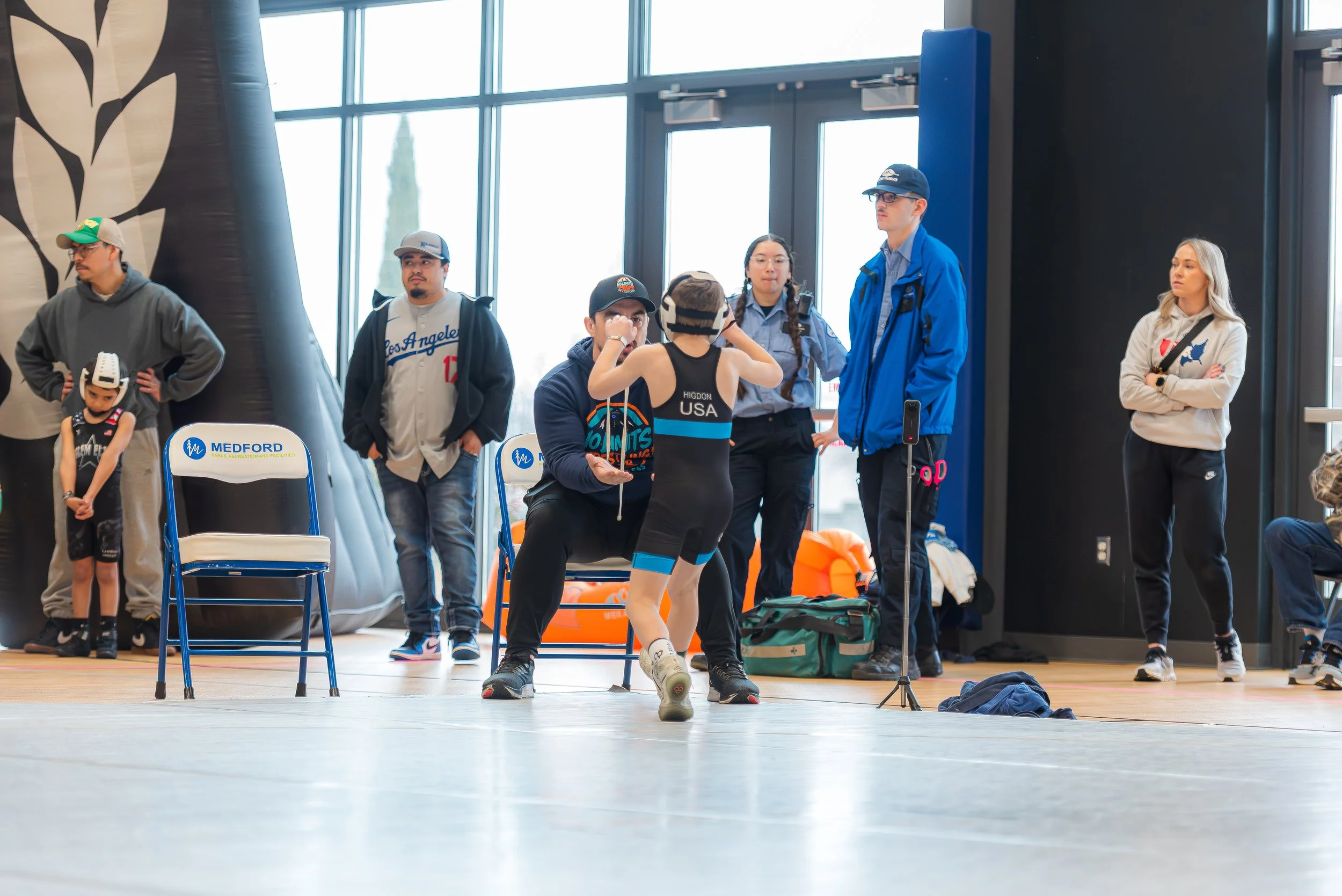 Youth wrestling coach calmly leading athletes during competition and long-term athletic development
