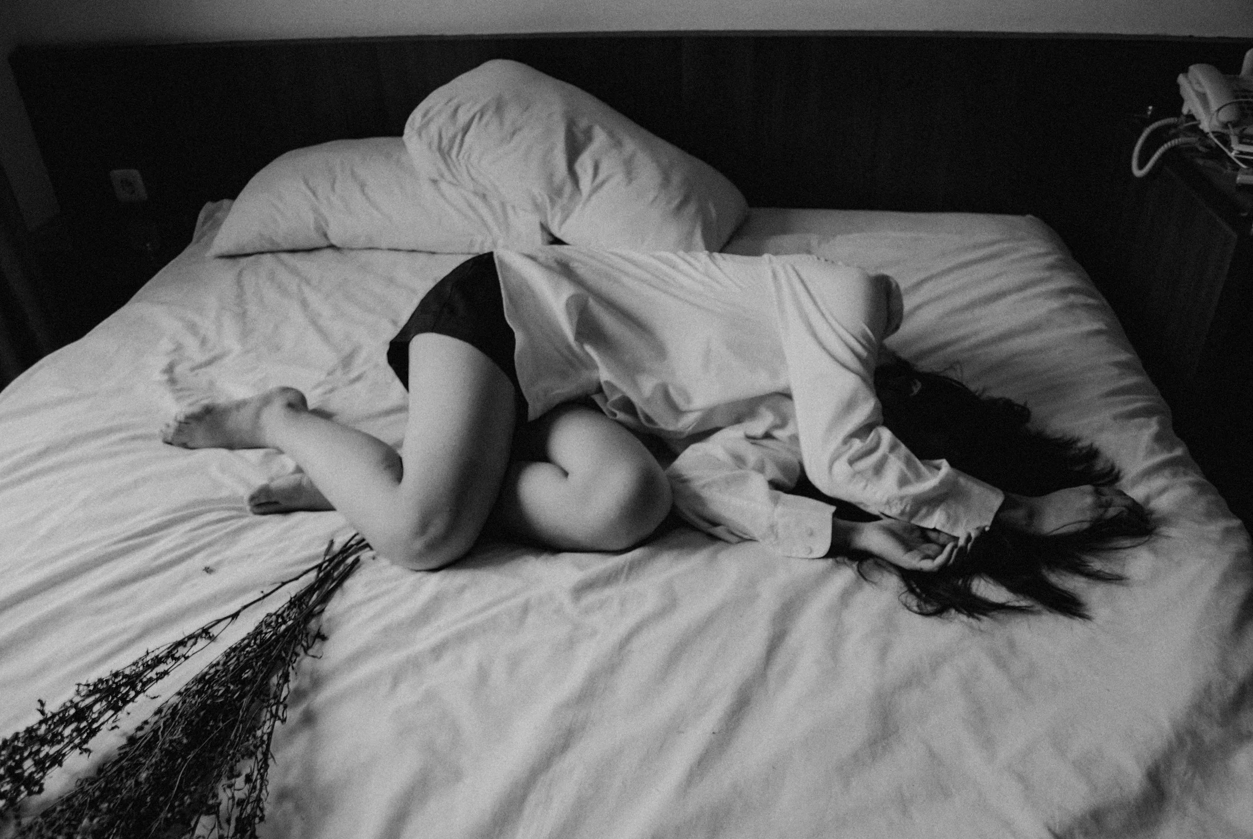 A woman laying on a bed feeling upset.