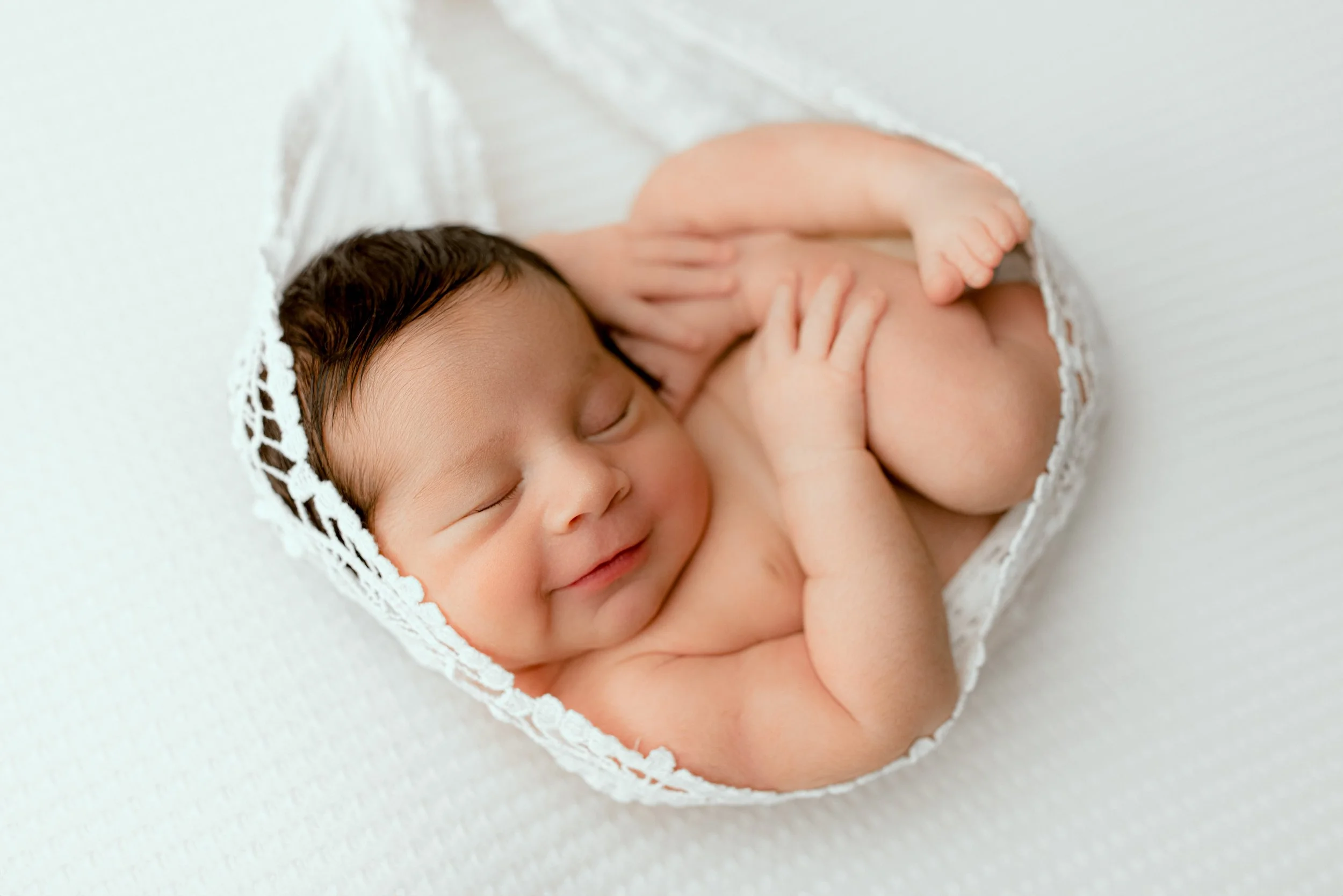 Newborn baby safely posed in a white studio setup in Bonney Lake