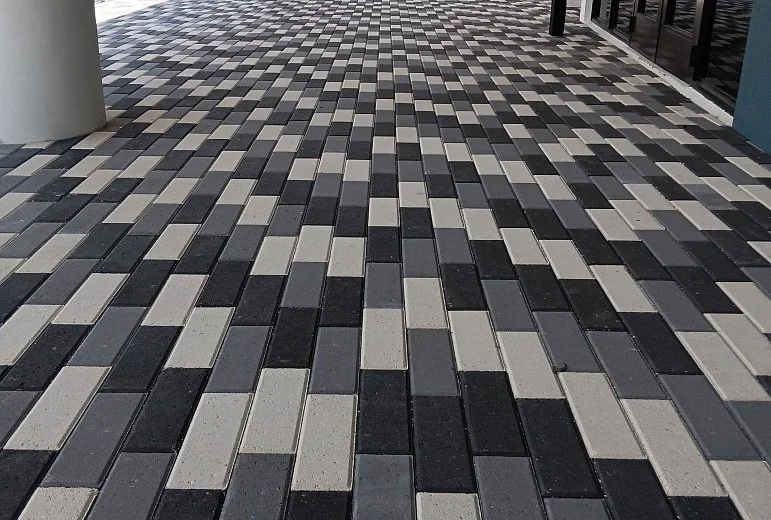 Patterned black, gray, and white paving stones on a sidewalk.