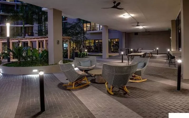 Outdoor hotel or apartment patio area at night with seating, rocking chairs, and ambient lighting