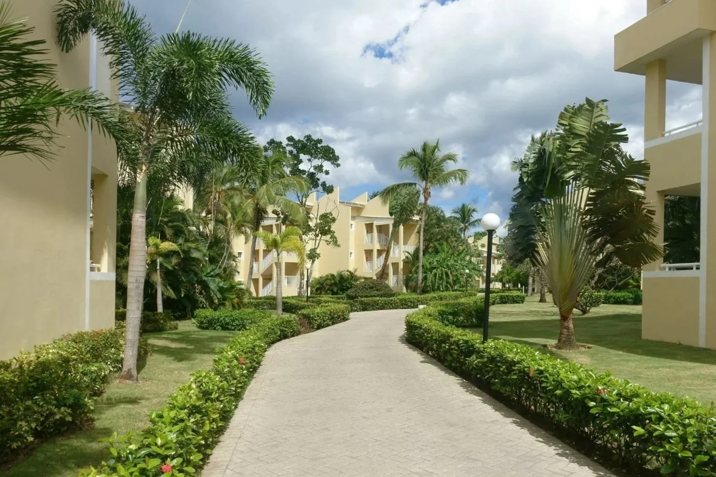 Residential community walkway with concrete pavers, tropical landscaping, and multi-family buildings in Jupiter, FL