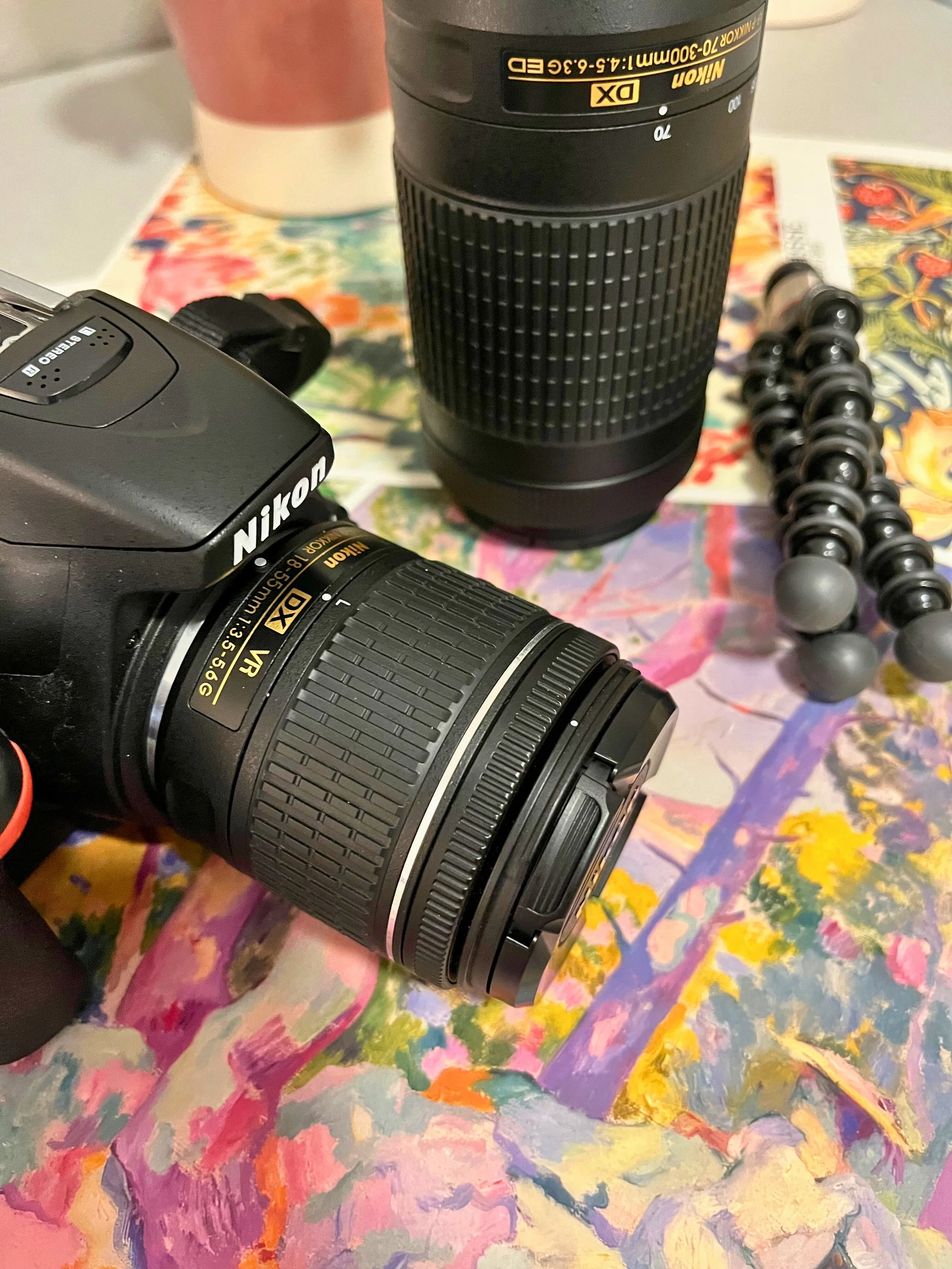 Image of a camera, extra lens, and tripod sitting on a table.