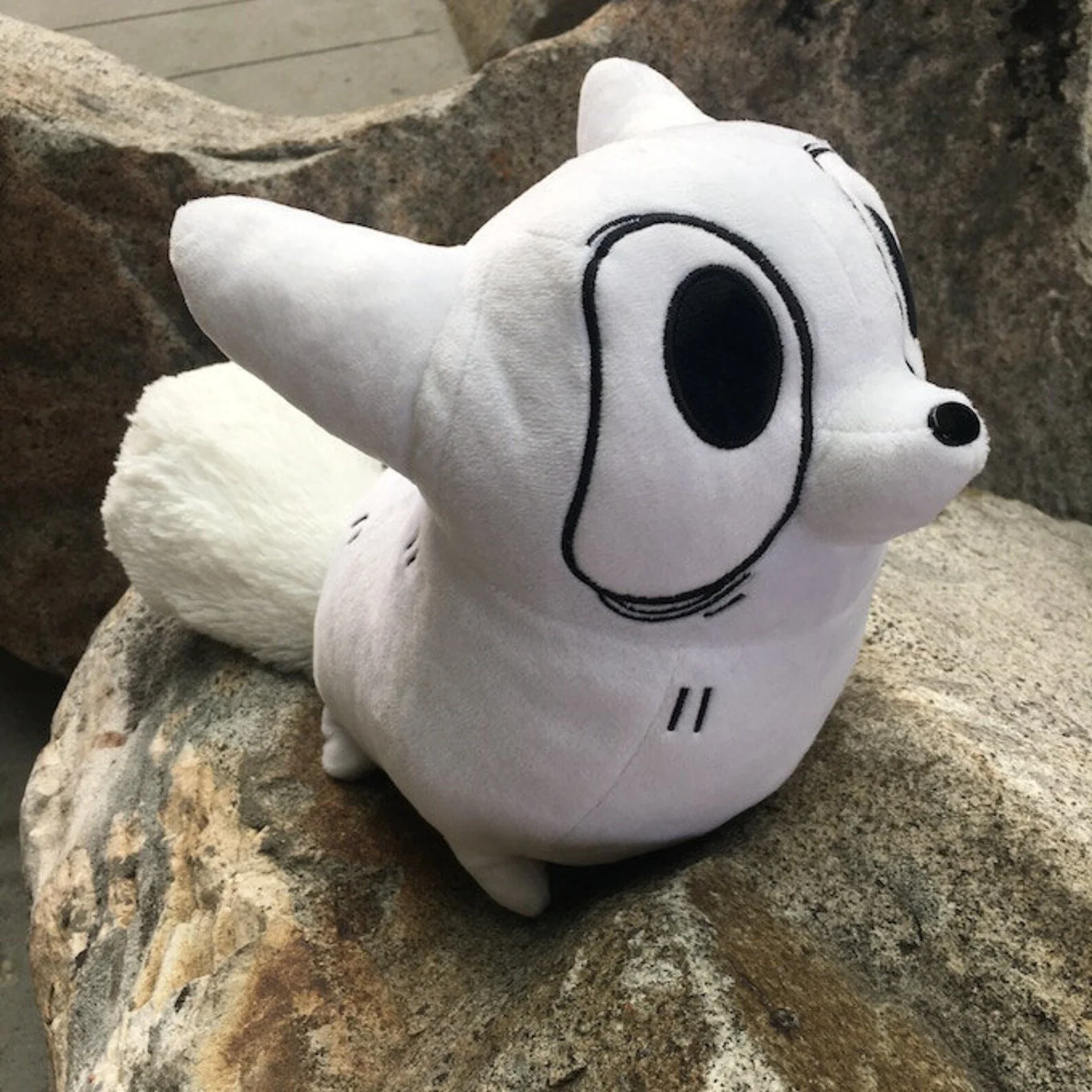 A plush toy of Anxiety Fox, sitting on a rock.