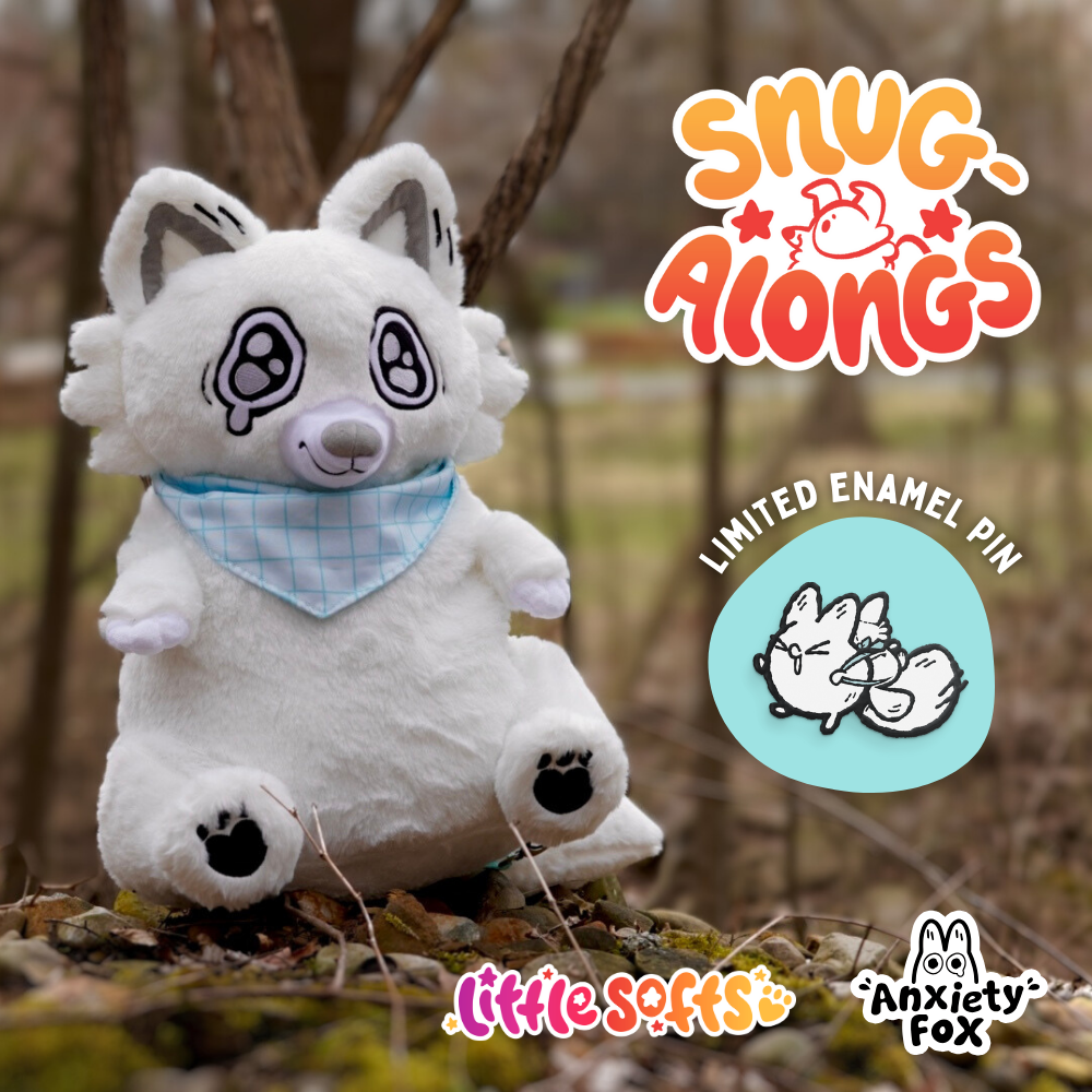 A plush white fox stuffed  with embroidered details, wearing a blue bandana, sitting outdoors on a mossy log in a wooded area. The image includes logos for "Snug-A-Longs," "Little Softs," "Anxiety Fox," and a sticker of a line drawing of a fox with the text "Limited Enamel Pin."