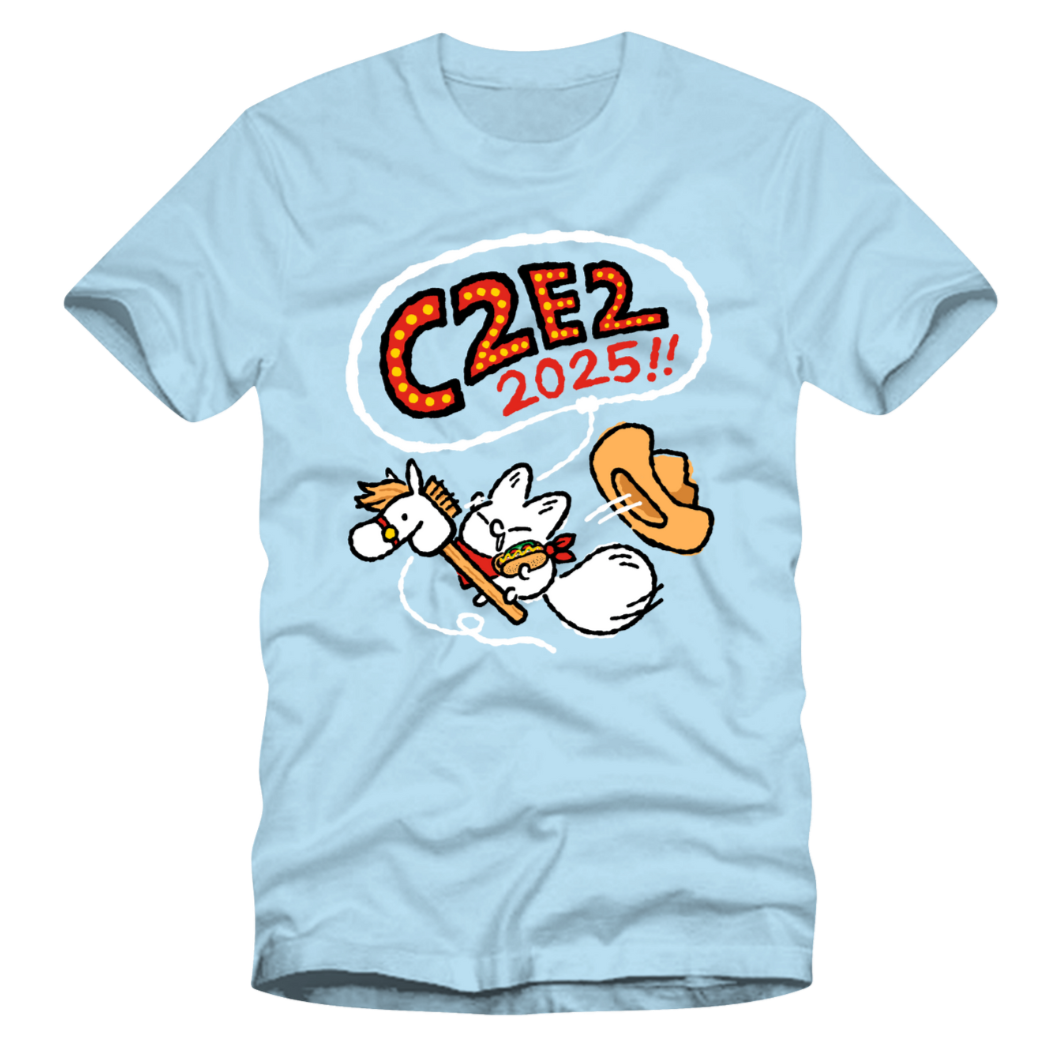 Light blue T-shirt featuring a cartoon fox playing a drum and holding a hot dog, with a speech bubble saying 'C22E2 2025!!' in colorful letters.