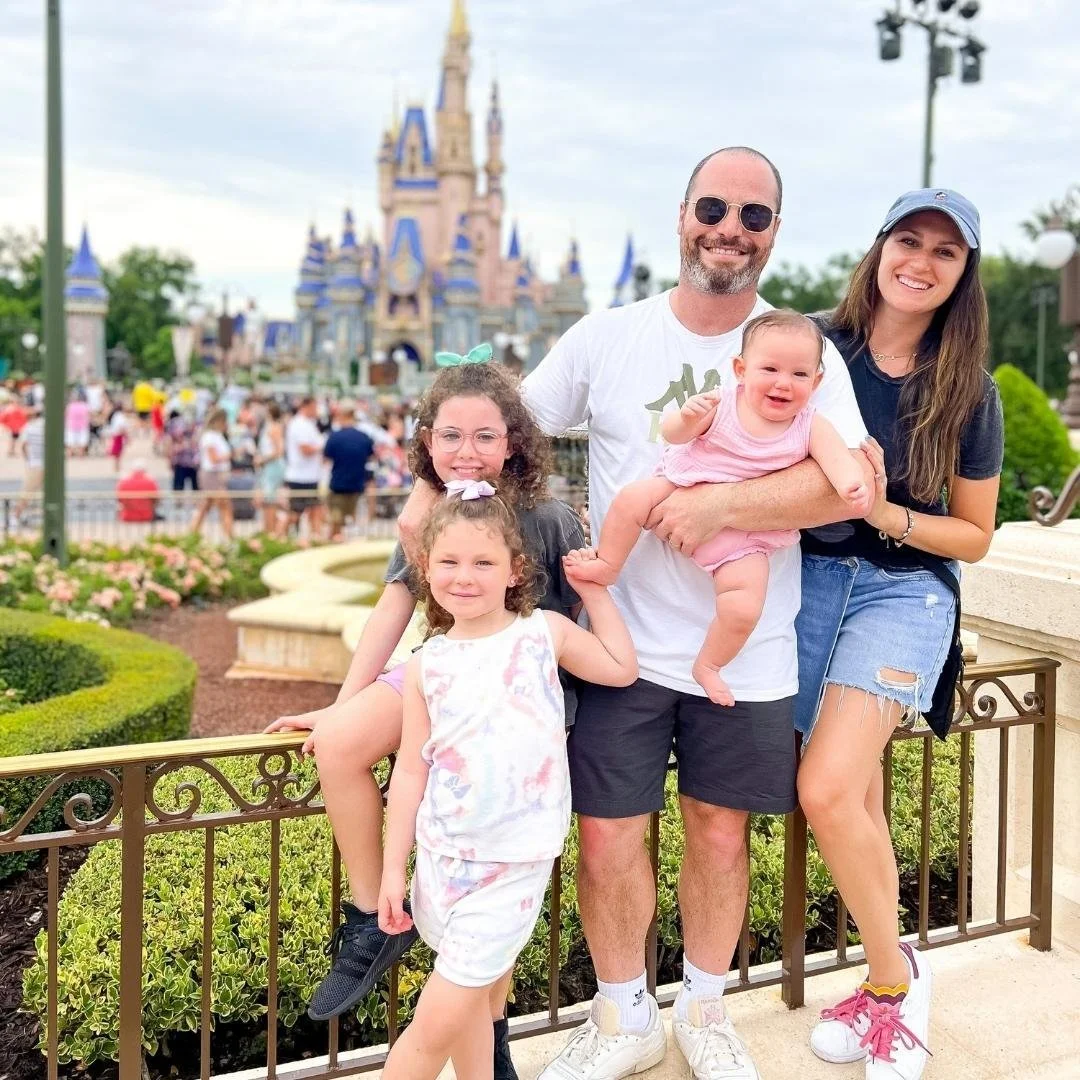Family of five posing in front of Disneyland castle during daytime.
