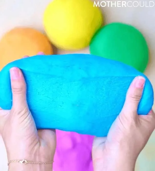 Person holding a blue stress ball with colorful balls in the background.