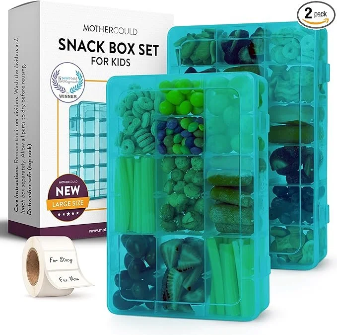A blue plastic snack storage box with multiple compartments filled with snacks, in front of a box labeled 'Mothercoud Snack Box Set for Kids,' including two packing tapes labeled 'For Stoy' and 'For Mom.'