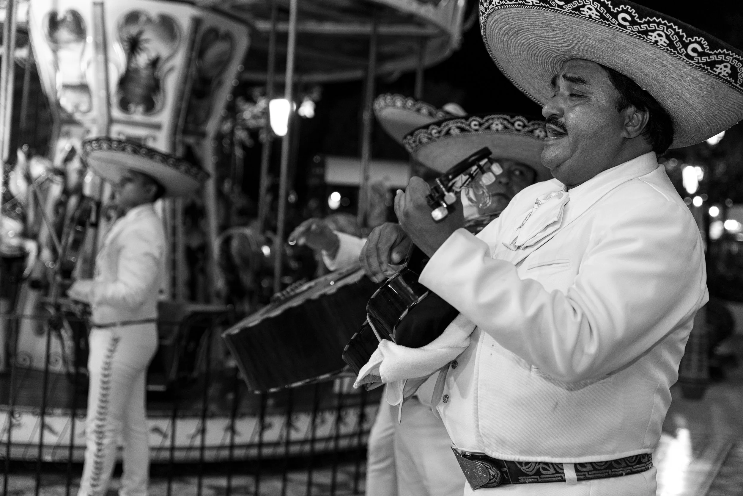 Men wearing traditional Mexican sombreros playing guitars at a festive event in black and white.