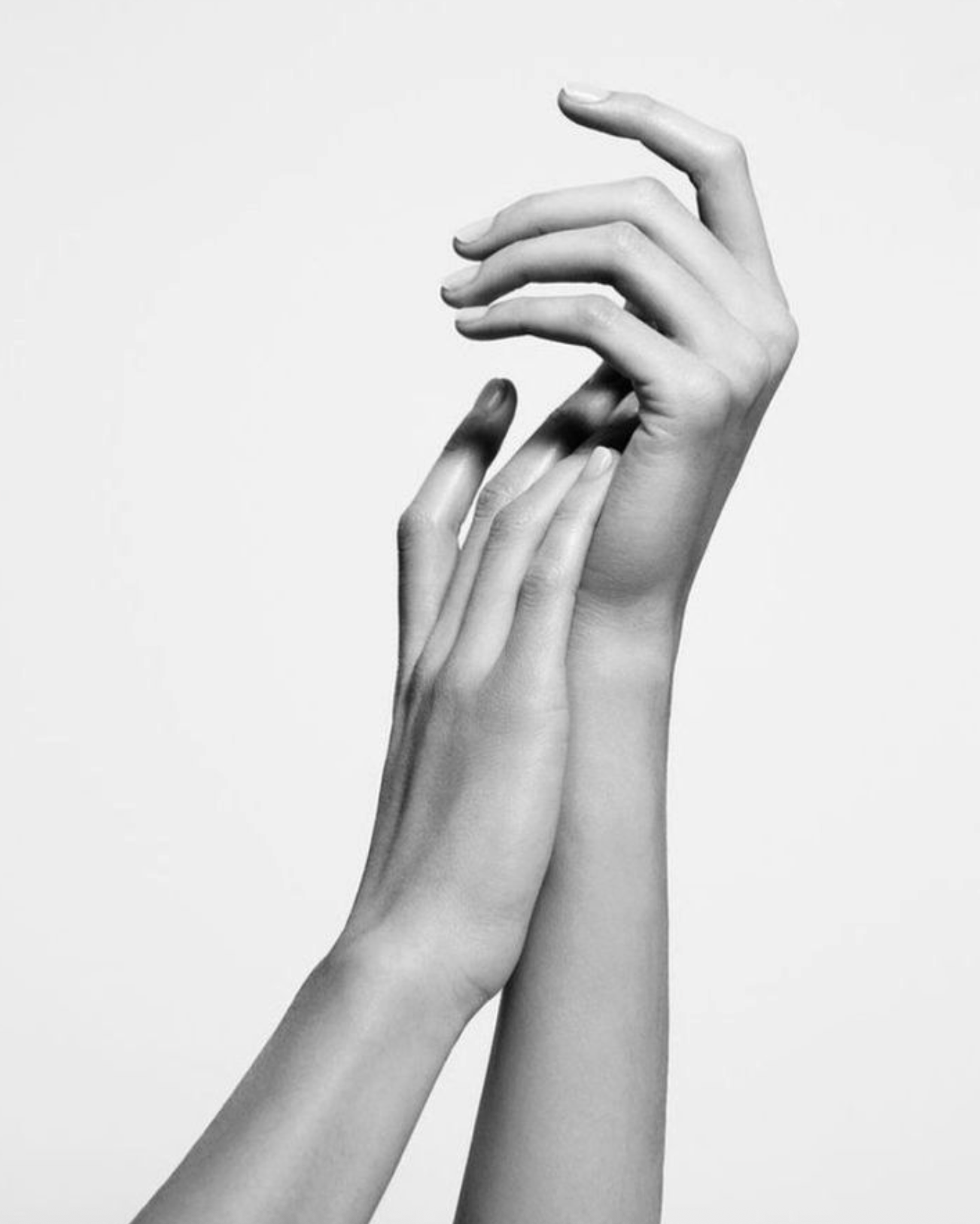 Two black and white hands reaching towards each other against a plain background.