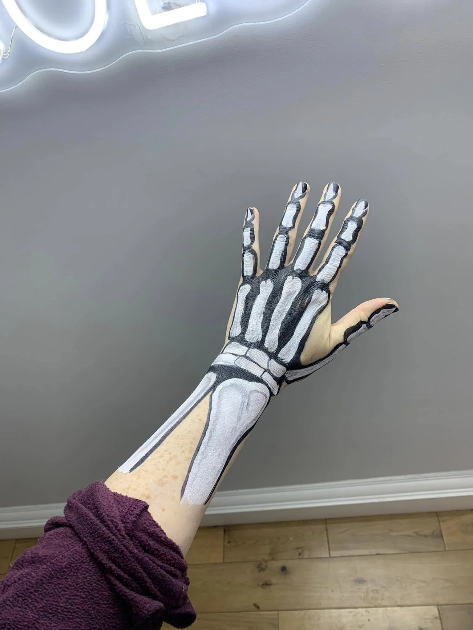 Face paint on arm. Skeleton of the arm painted in white and black showing bones aligned with the actual hand and arm structure.