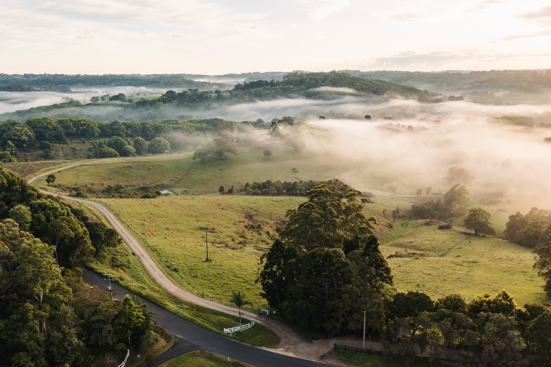 Misty rolling hills and winding road in the Byron Bay Hinterland creating a peaceful and secluded setting for a private wellness retreat