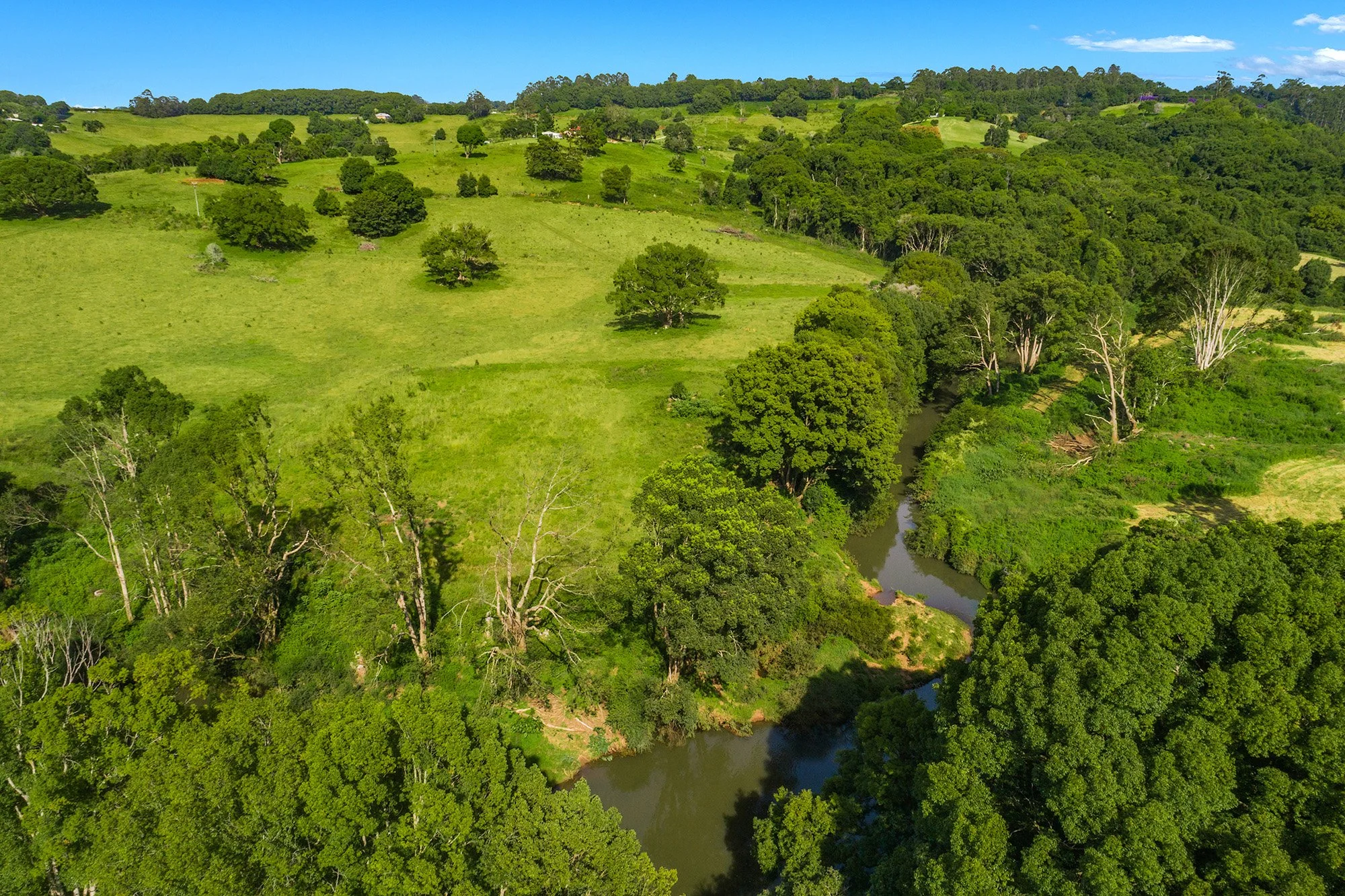 River winding through lush green landscape at Heartwood Farm Byron Bay private wellness retreat