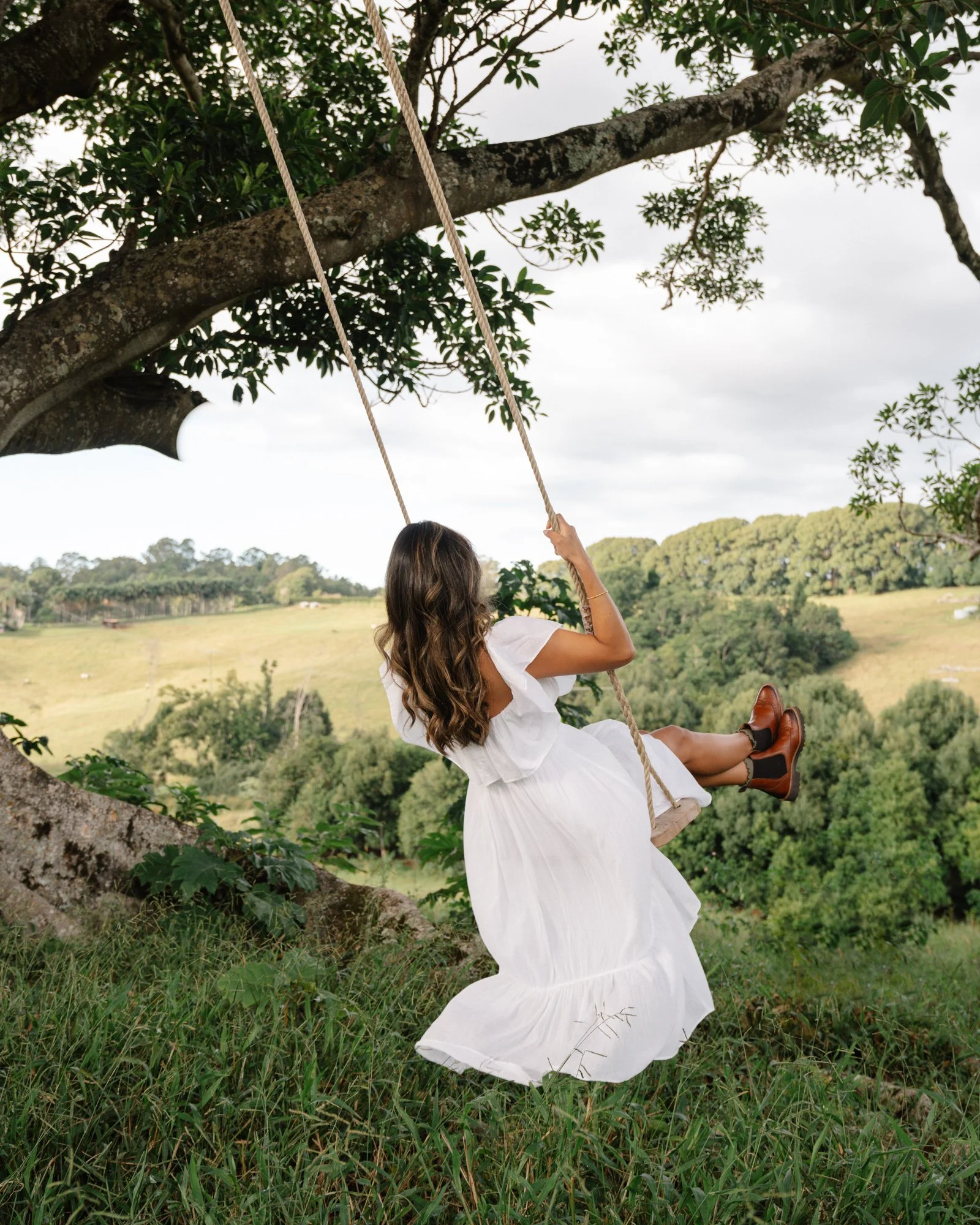 Woman on tree swing overlooking rolling hills at a private retreat venue in the Byron Bay Hinterland
