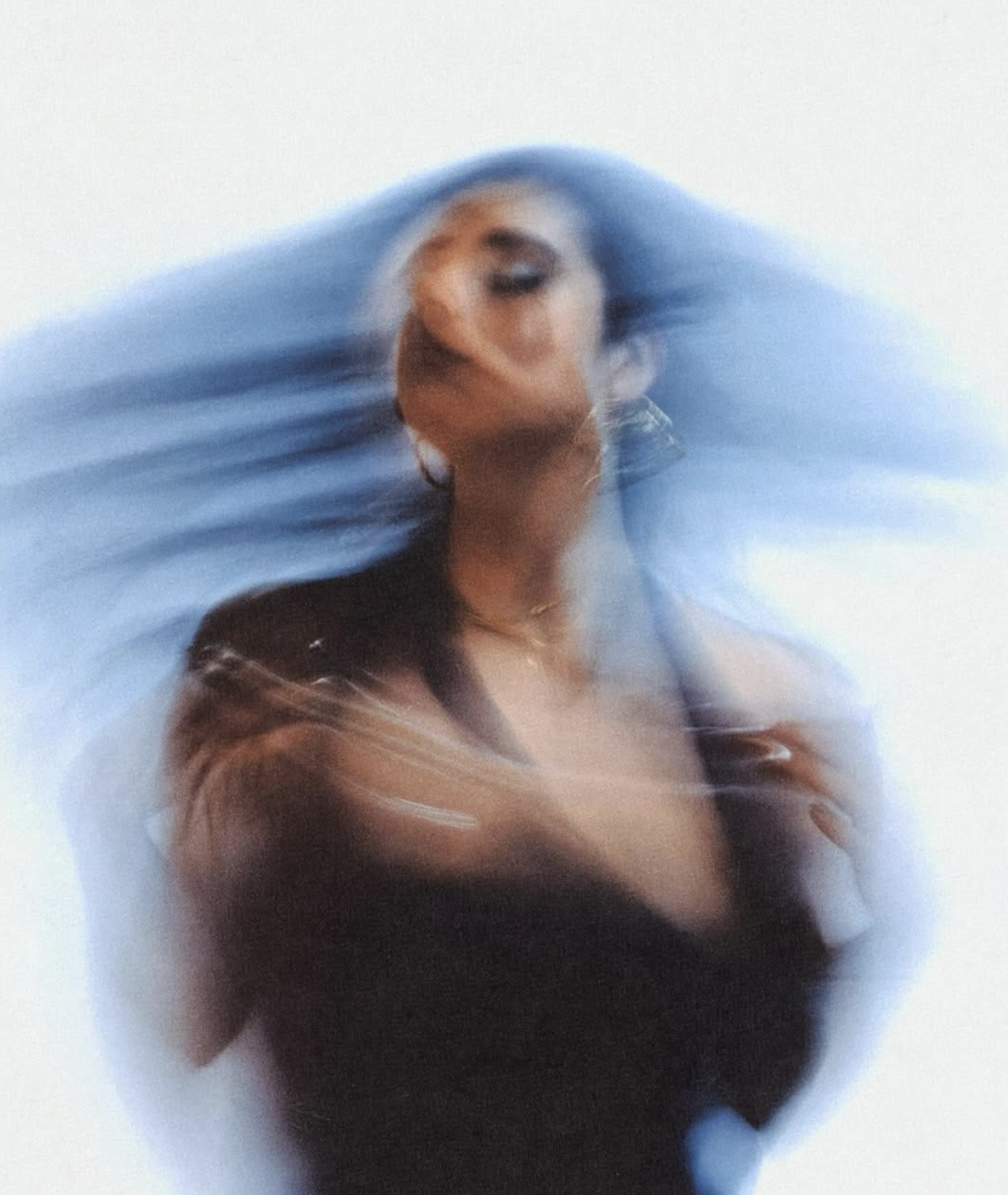 A woman with long hair is moving quickly, creating a blurred effect, with her face turned slightly away and her hair blowing to the side.