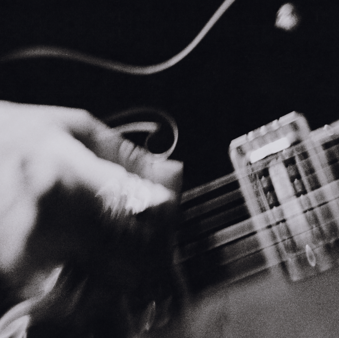 A person's hand tuning the headstock of an electric guitar with a string and tuning peg visible