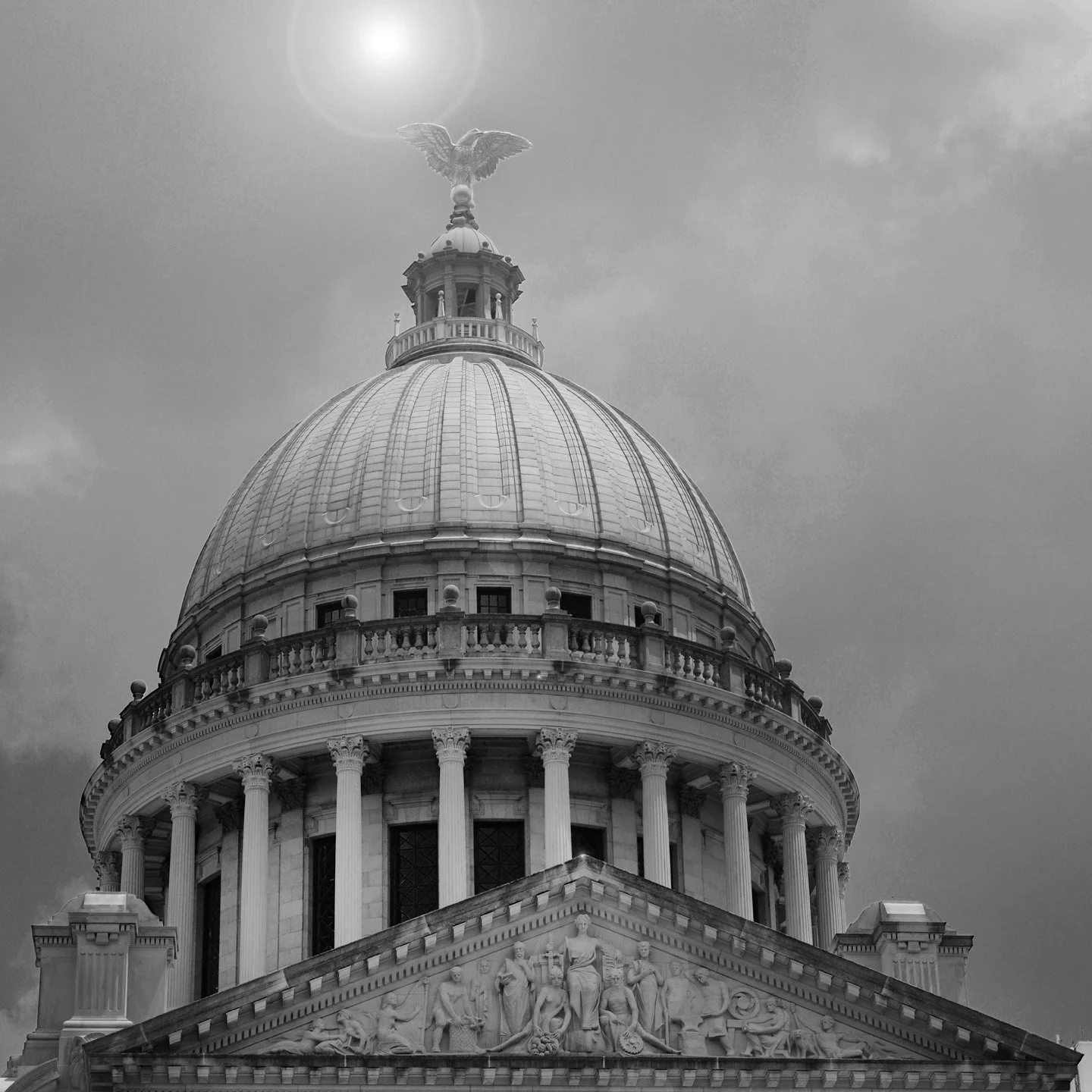 Black and white photo of a Mississippi State Capitol with classical architecture, a large dome, and a statue of an eagle at the top.