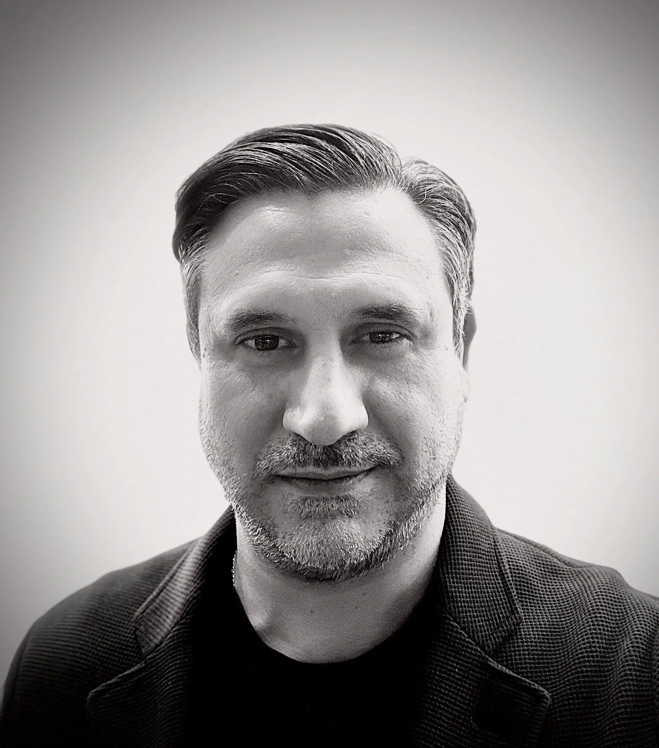 Black-and-white portrait of a man with short, dark hair, a beard, and wearing a collared shirt.