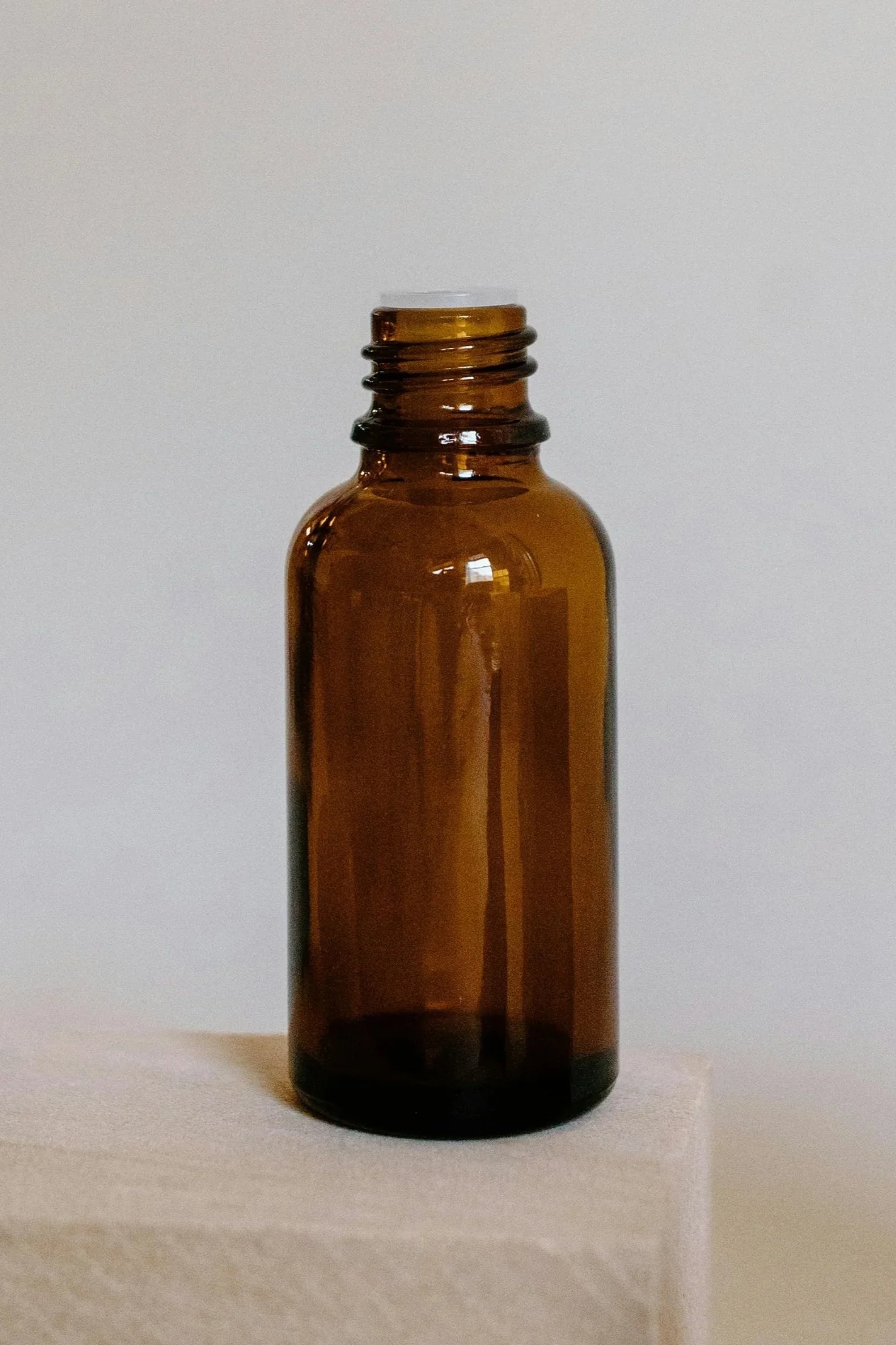Empty brown glass bottle placed on a light-colored surface against a plain white background.