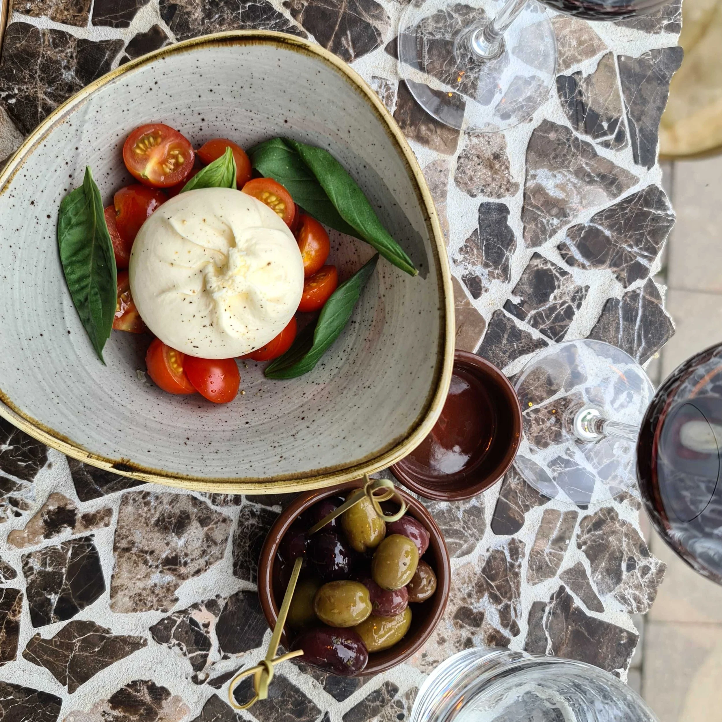 Bar1103 - Plejede at servere lækker charcuterie og snacks på Vesterbro. Her ses deres burrata, med tomat og frisk basilikum med tilhørende græske oliven. Idag afvikler Bar1103.dk cocktailkurser og cocktail catering og driver ikke længere restaurant.
