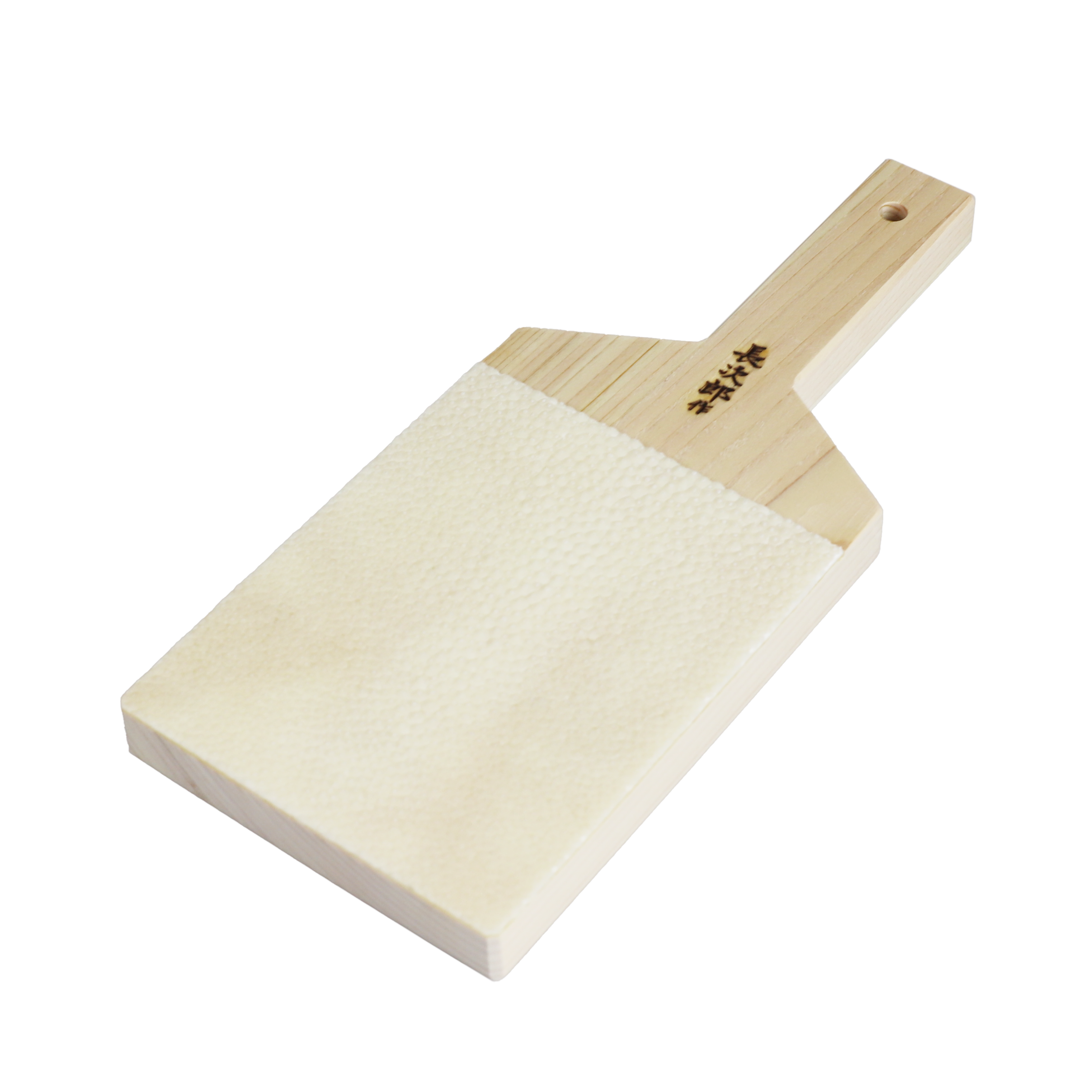 A wooden game piece or block with Japanese characters engraved on it, resting on a textured white surface.