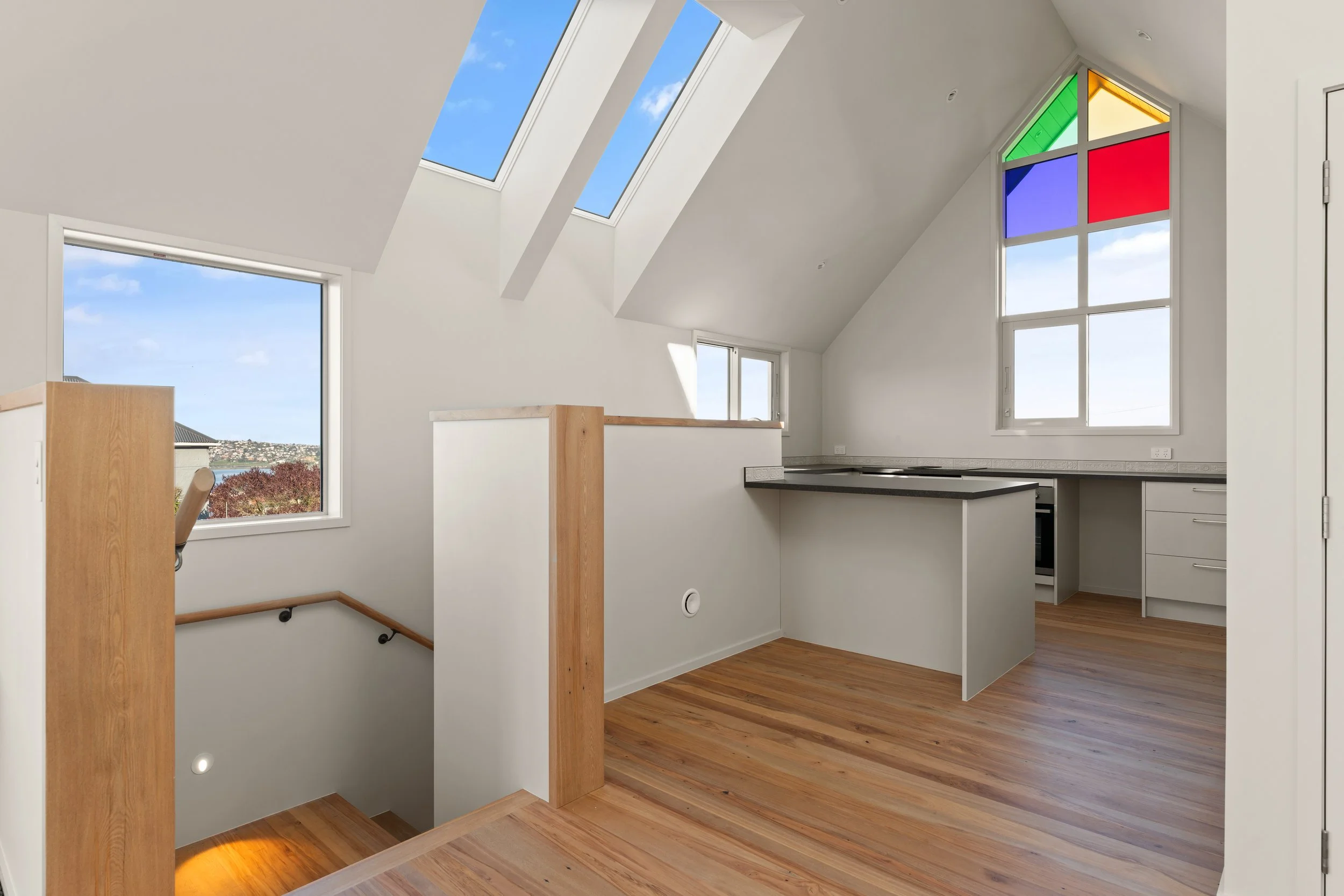 Brightly lit kitchen with skylights, Windows, hardwood floors, and colorful stained glass window. Passive house principles, high performing, warm and dry. Solar power. 