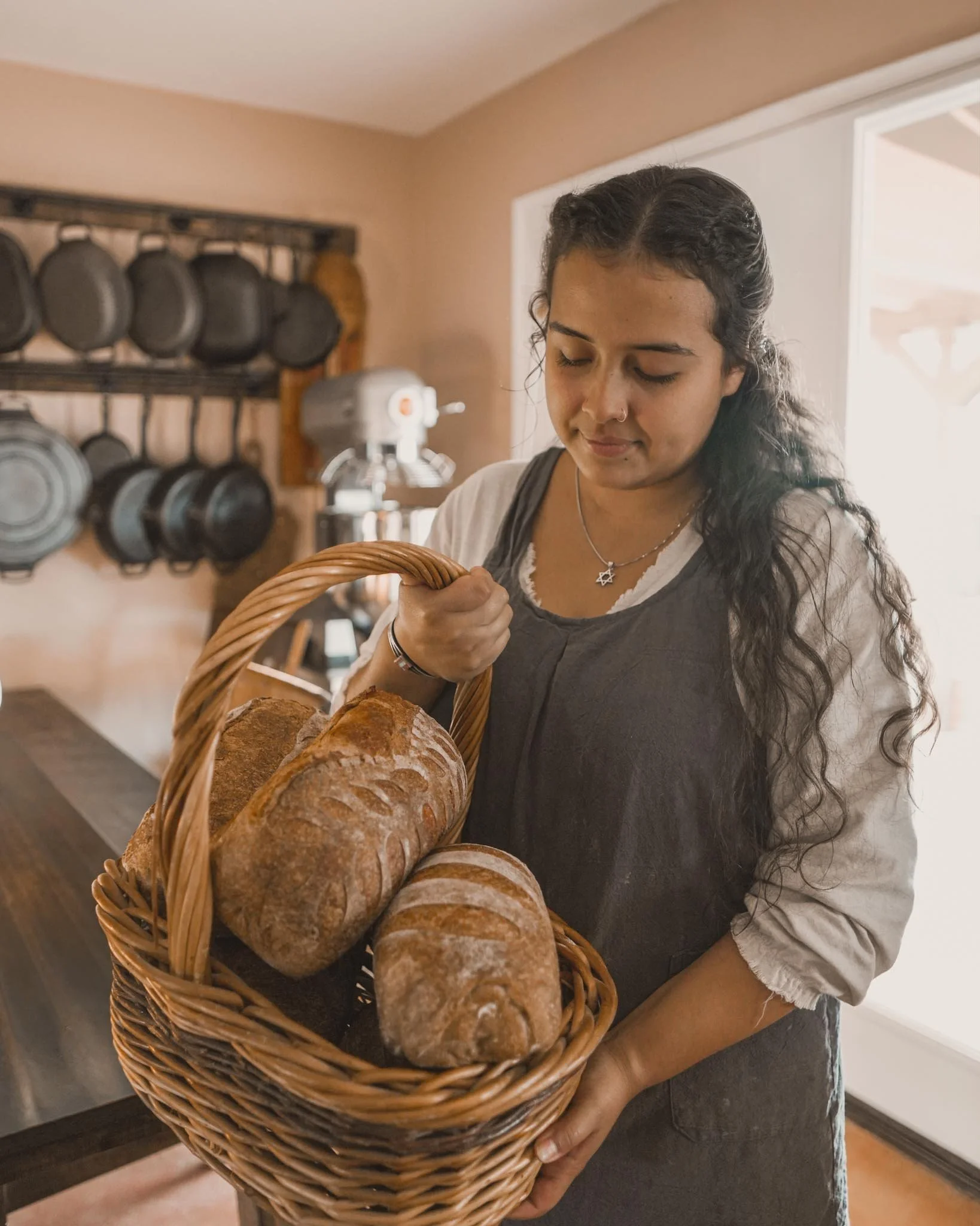 Woman holding a basket of freshly baked bread in a cozy kitchen.