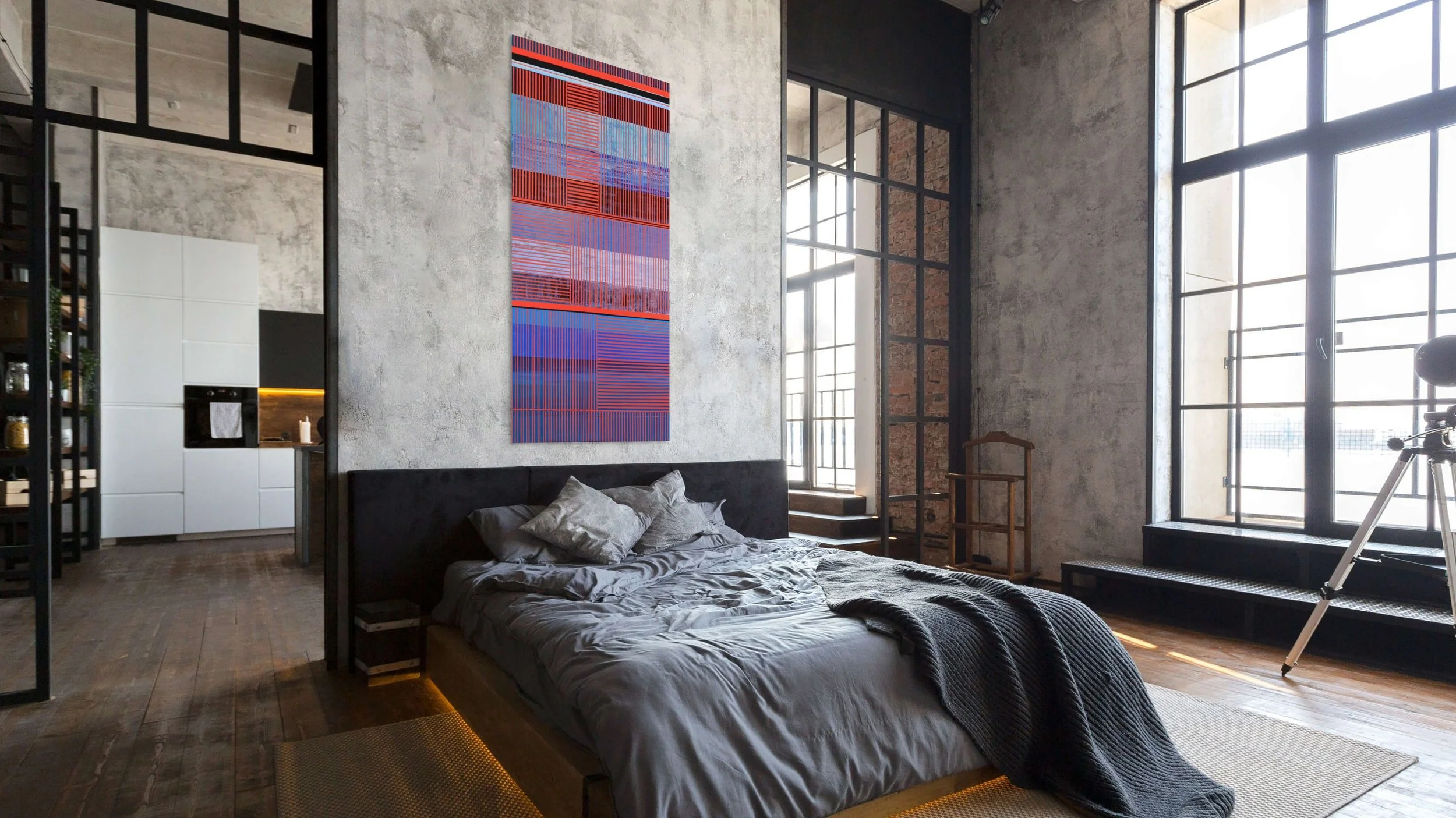 A modern bedroom with large windows, a gray bed with crumpled gray sheets and pillows, a dark headboard, a textured concrete wall with colorful abstract artwork, and a telescope near the window. A doorway leading to a kitchen with white cabinets and 