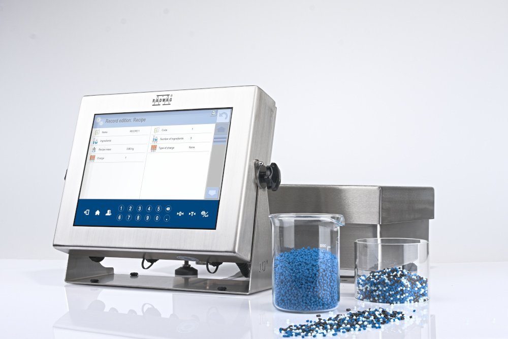 A medical device with a touchscreen interface, alongside two clear containers filled with small blue and white granular materials.
