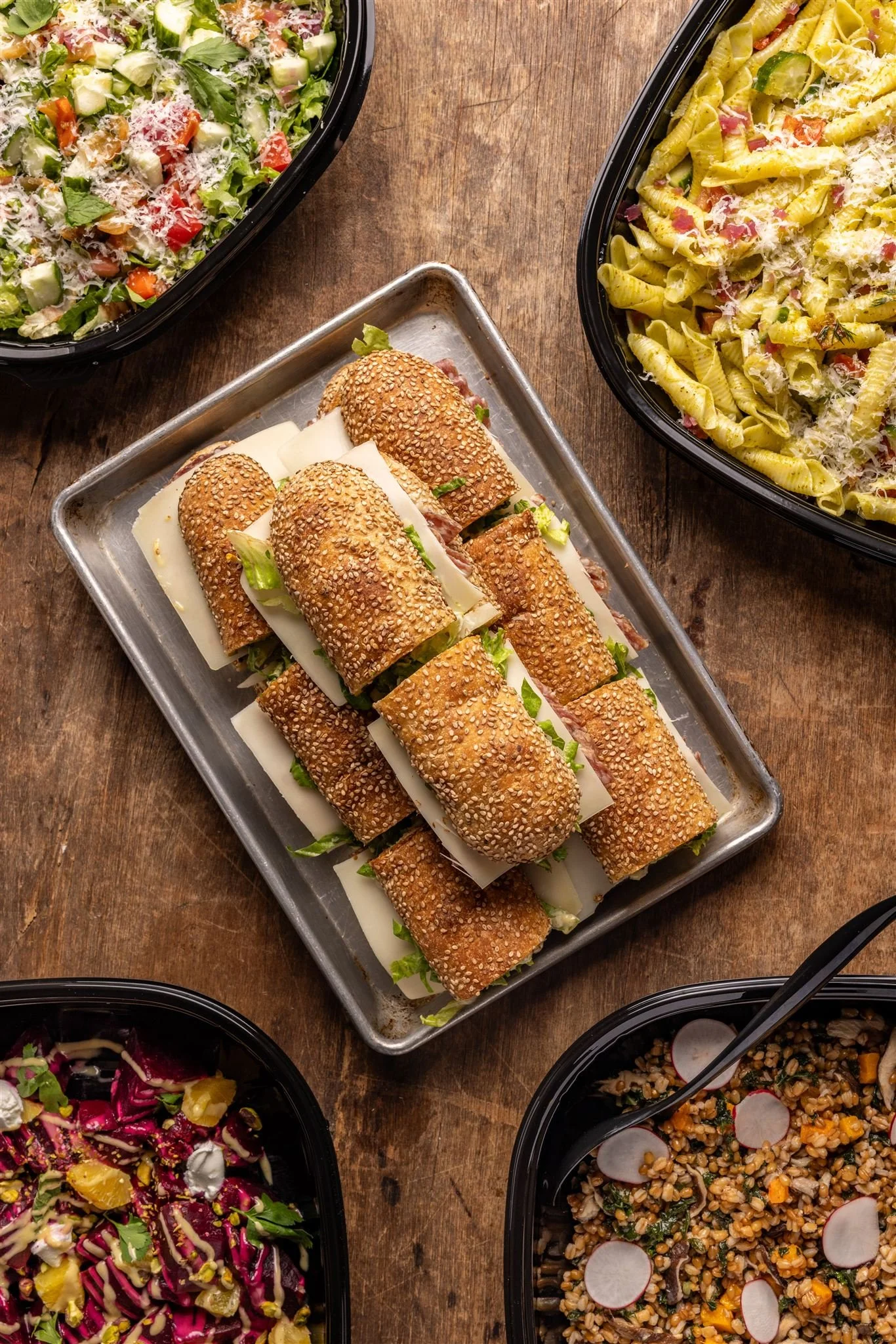 Sandwiches on a tray and large bowls of salad.