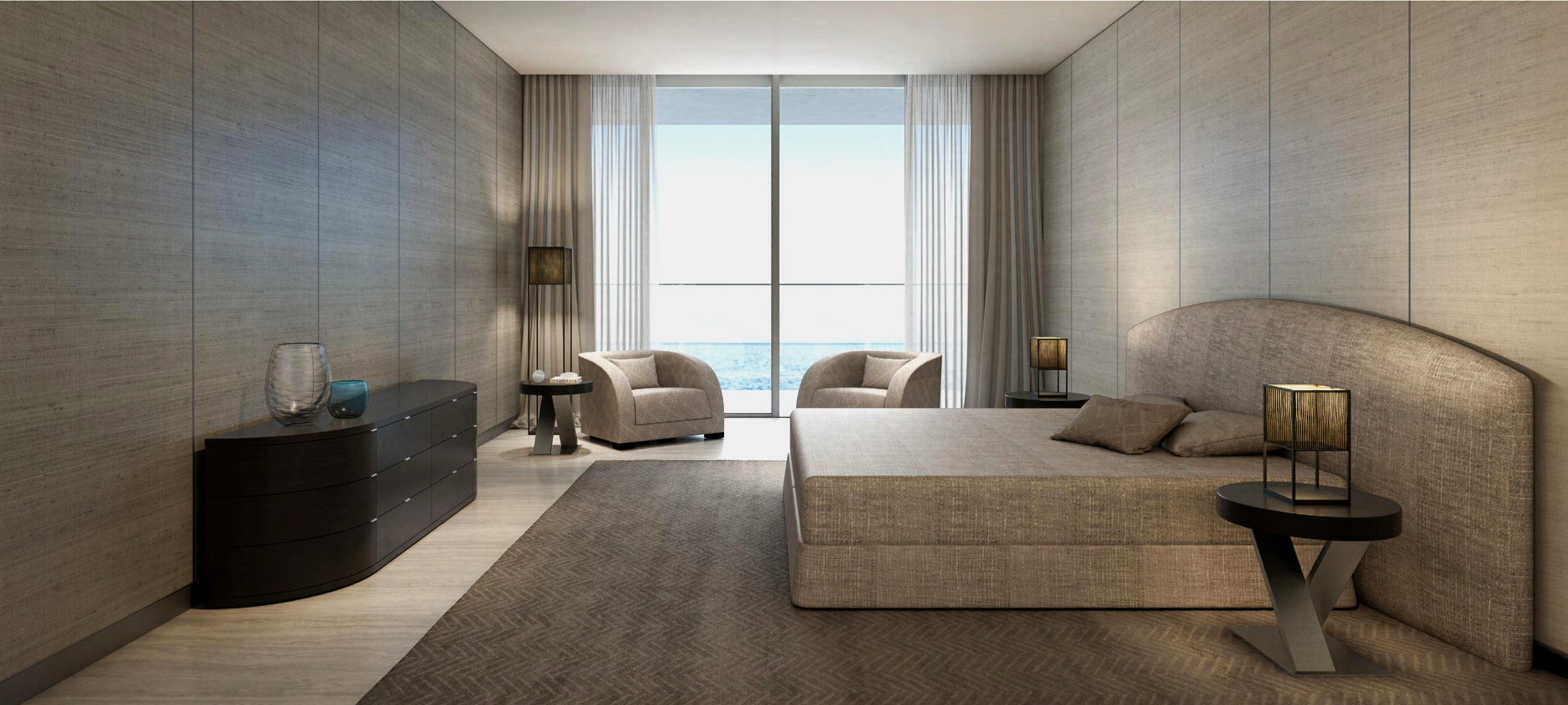 A modern hotel room with a large bed, nightstands with lamps, two armchairs with a small table, and a sliding glass door leading to a balcony overlooking the ocean.