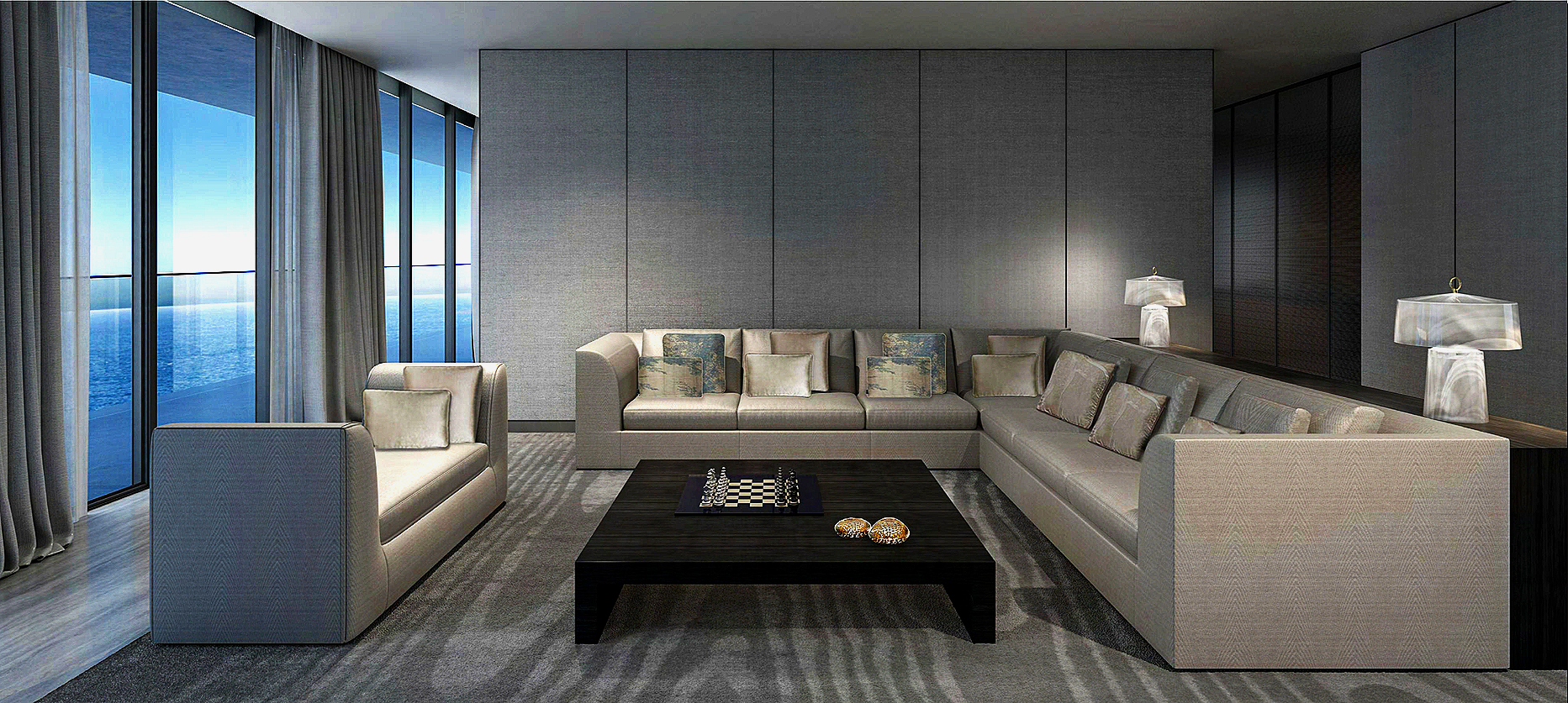 Modern hotel living room with large windows showing the ocean, light-colored sofas with decorative pillows, a black coffee table with a chessboard, and two table lamps on side tables.