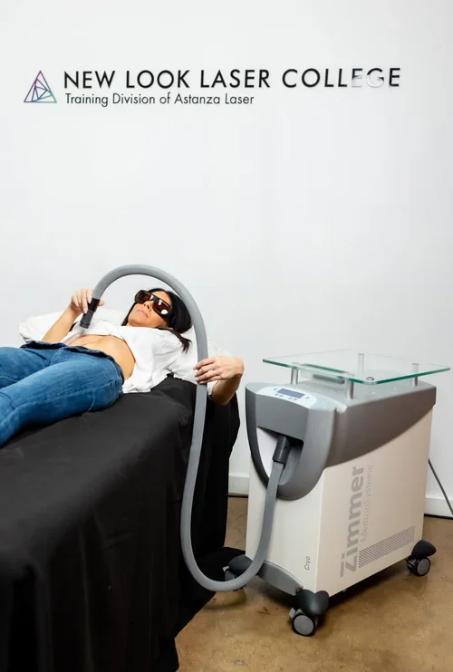 Person lying on a treatment bed with laser goggles during a laser hair removal procedure at New Look Laser College, with equipment nearby.