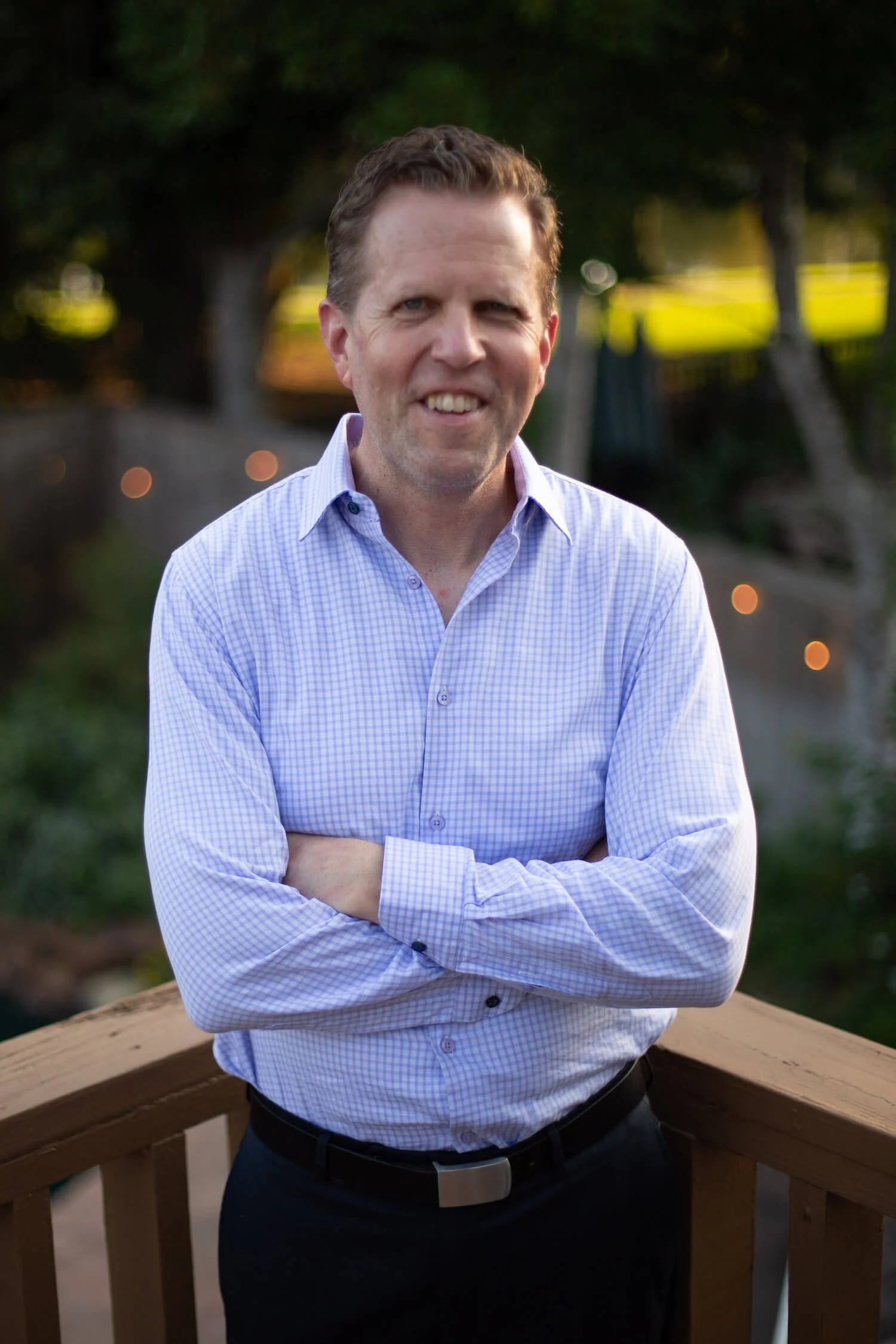 Executive coach Brian Owen in a light blue shirt with arms crossed, standing outdoors