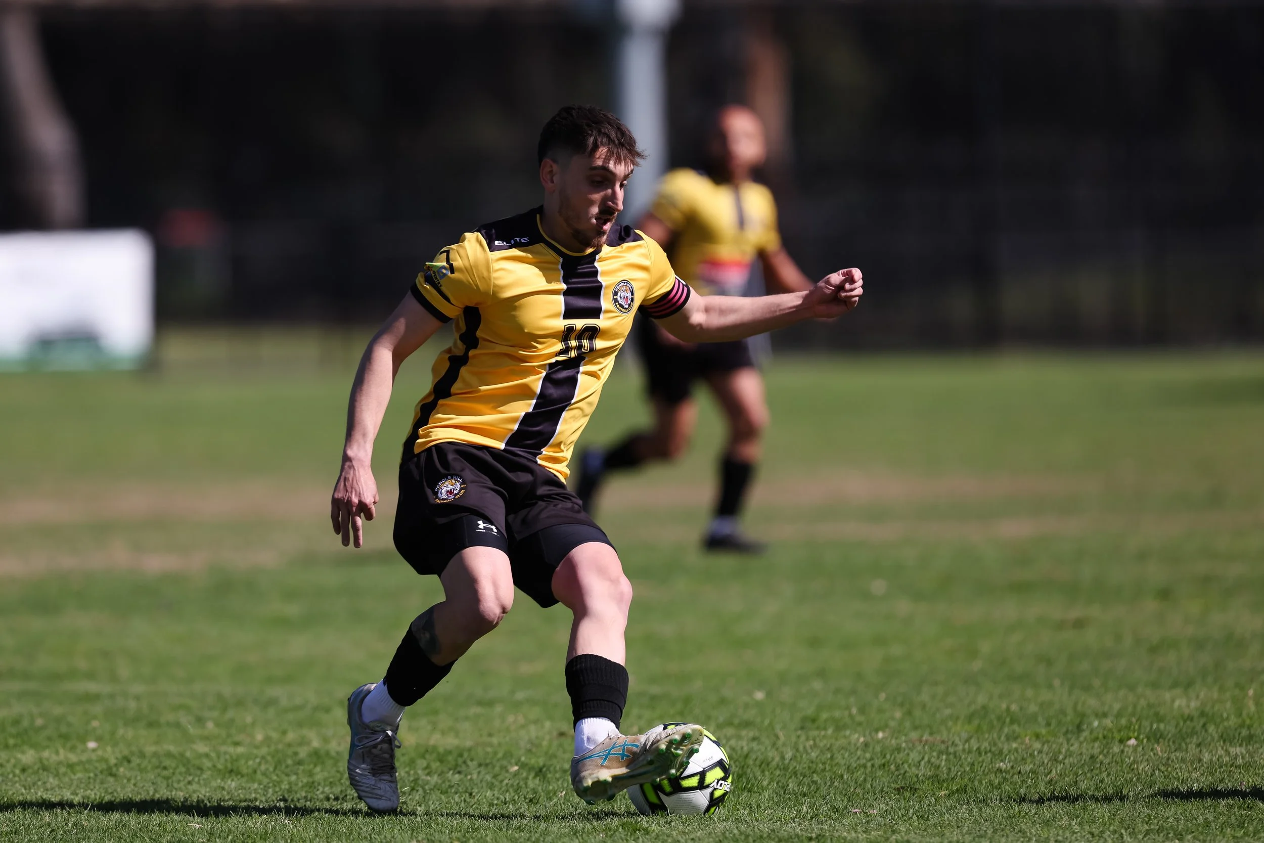 Soccer player in black and gold controling a football.