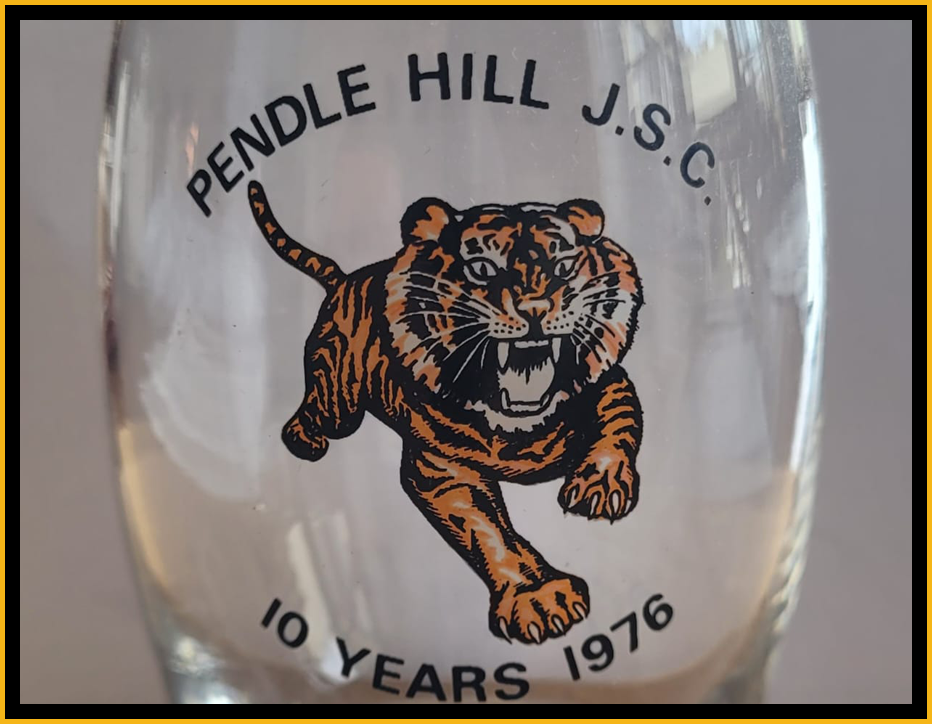 A glass with a logo of a running tiger and the text "Pendle Hill J.S.C. 10 Years 1976".