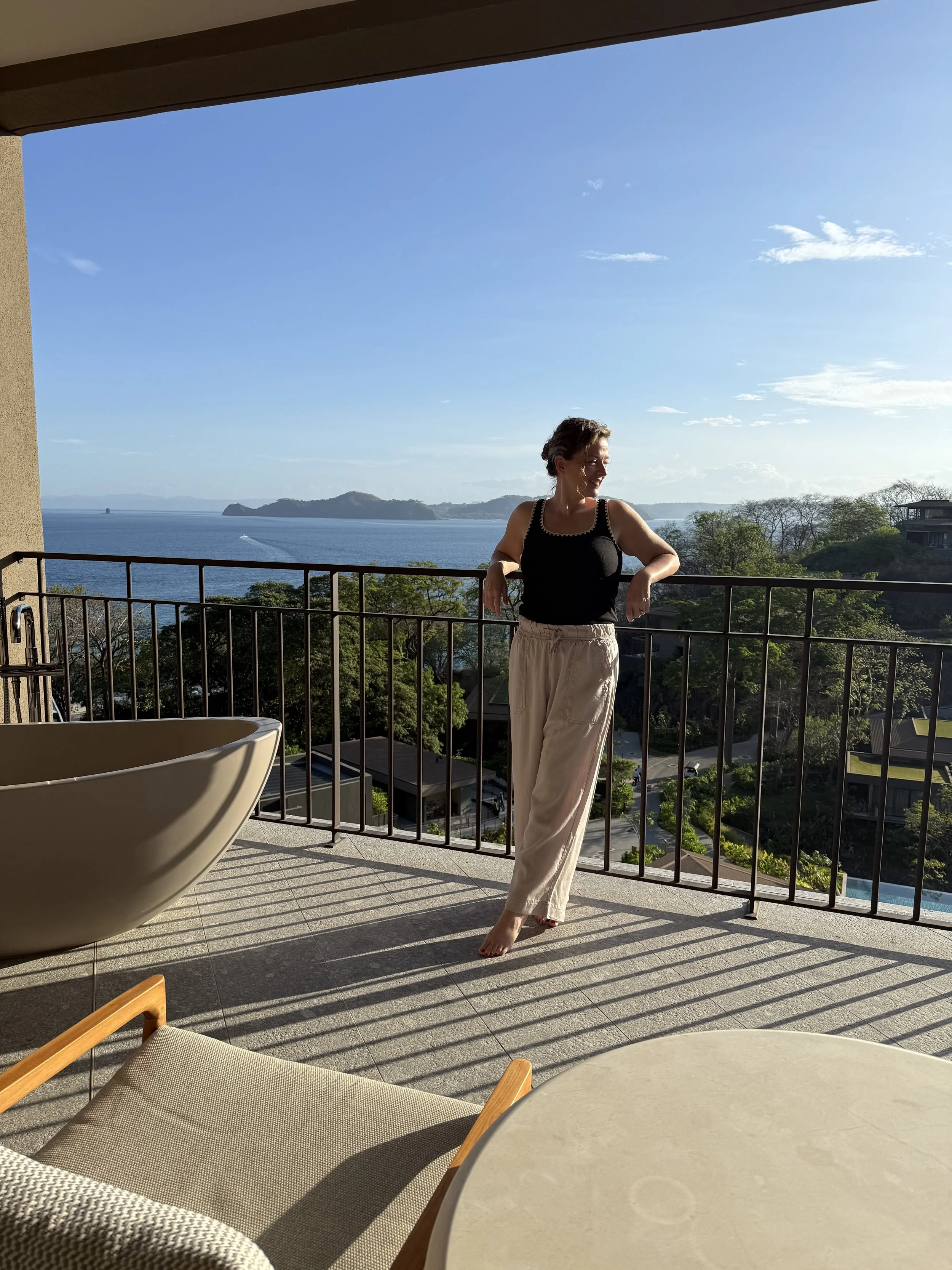 Ciara of Salt + Serenity Travel on the balcony at Waldorf Astoria Punta Cacique overlooking the sunlit coastline