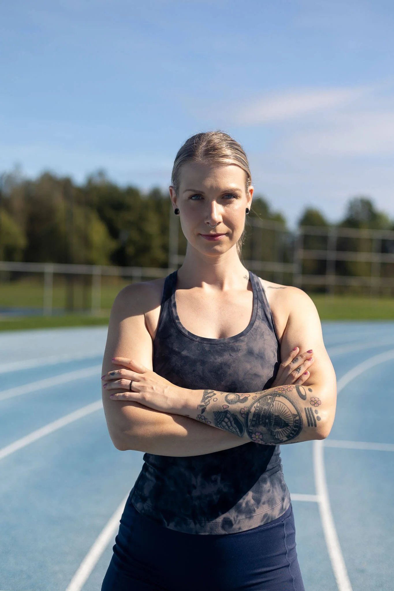 woman is posing on a running tack in an athletic outfit