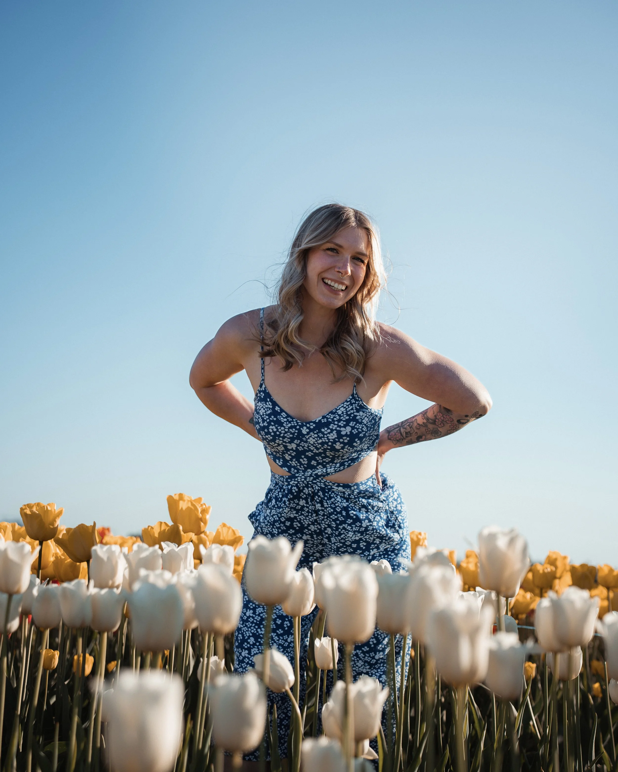 a woman in a blue and white dress poses in a tulip field
