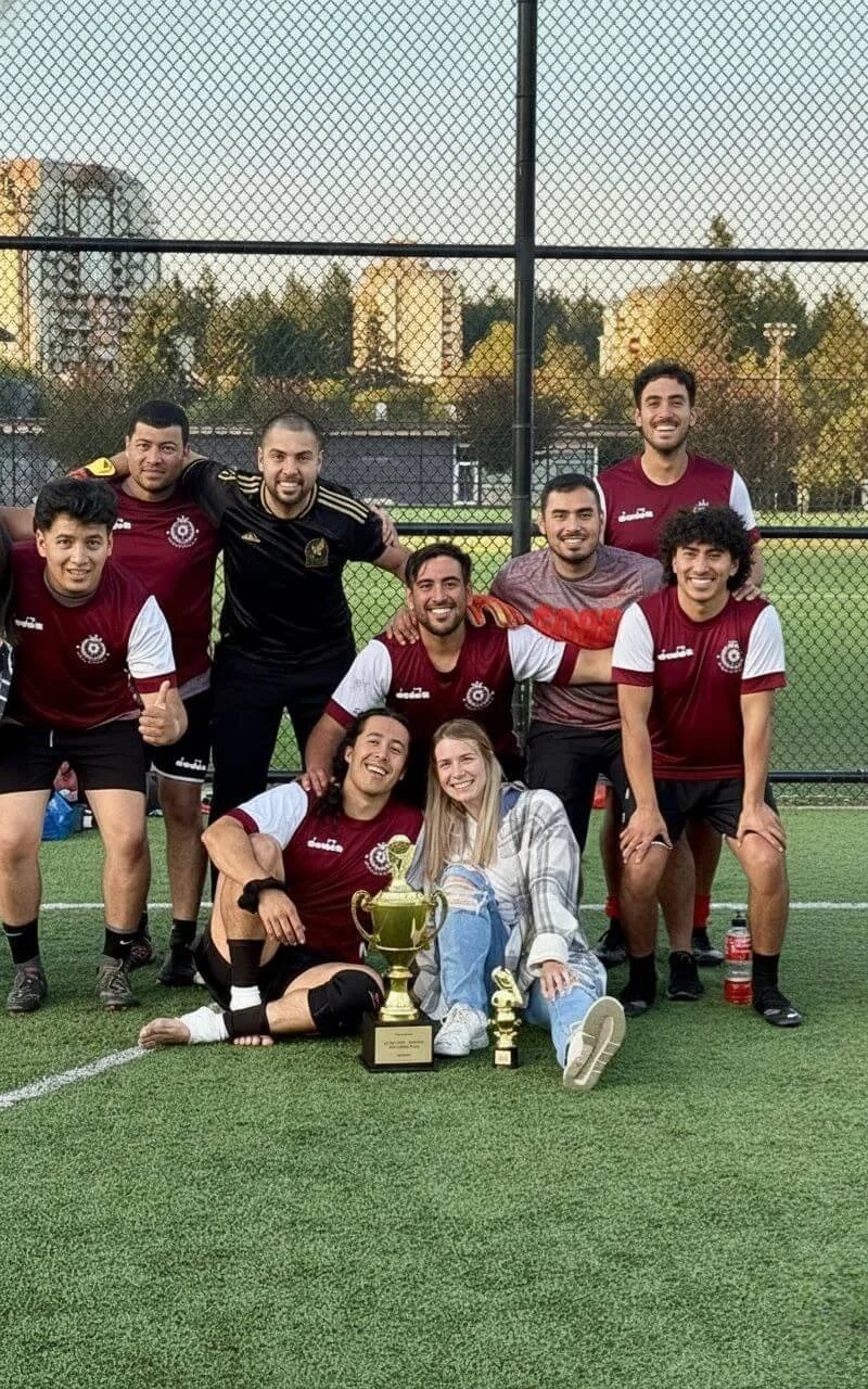 woman poses for group photo with soccer team showing off their championship trophies