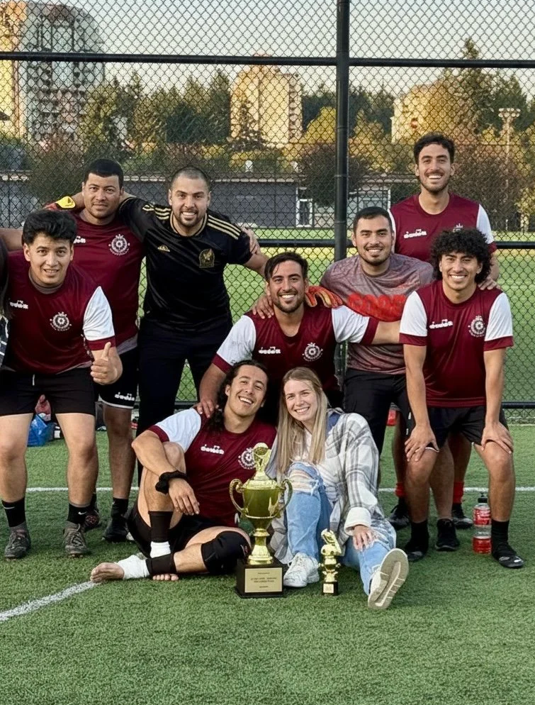 A soccer team is huddled for a group photo. their sports nutritionist takes a photo with the team