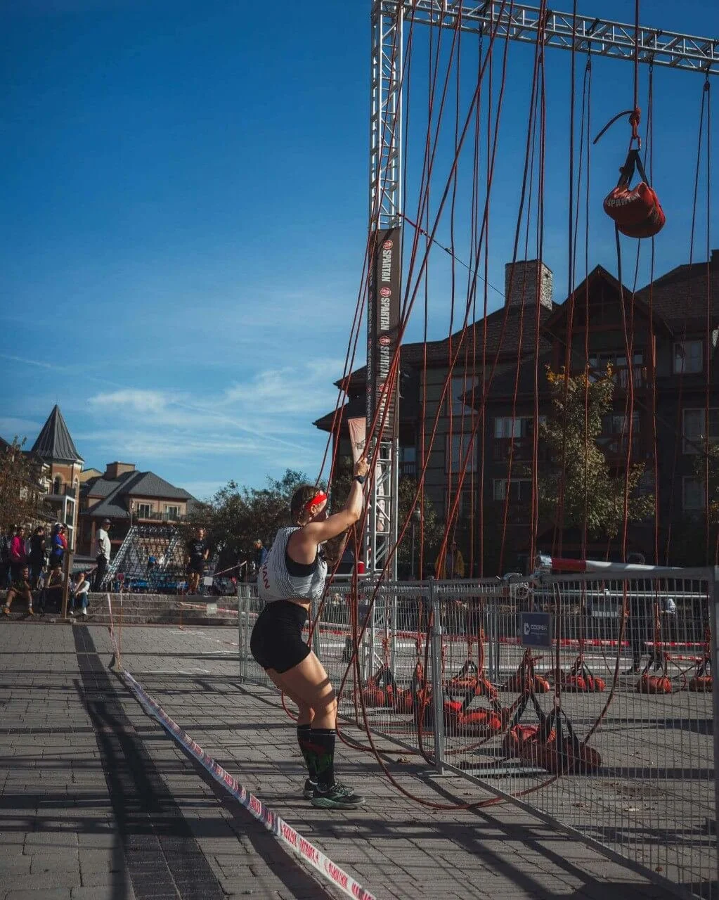 woman in a red headband outdoors is pulling on a sandbag in a spartan race