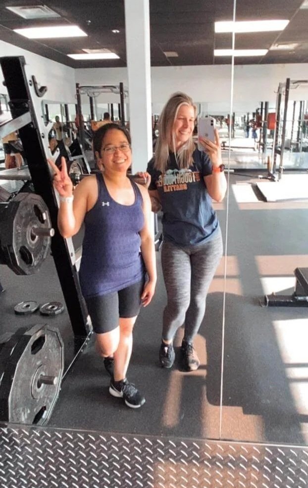 Two women at the gym posing in the mirror