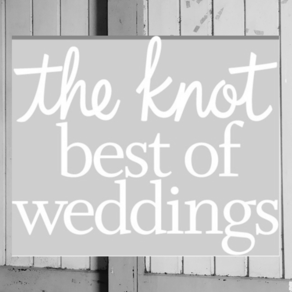 Sign that reads "the knot best of weddings" in white cursive and print letters on a gray background mounted on a wooden wall.