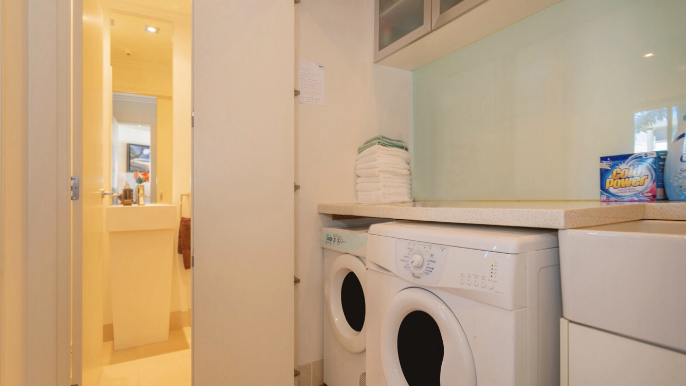 Laundry room with stacked towels, a washing machine, and a dryer, adjacent to a bathroom entrance.
