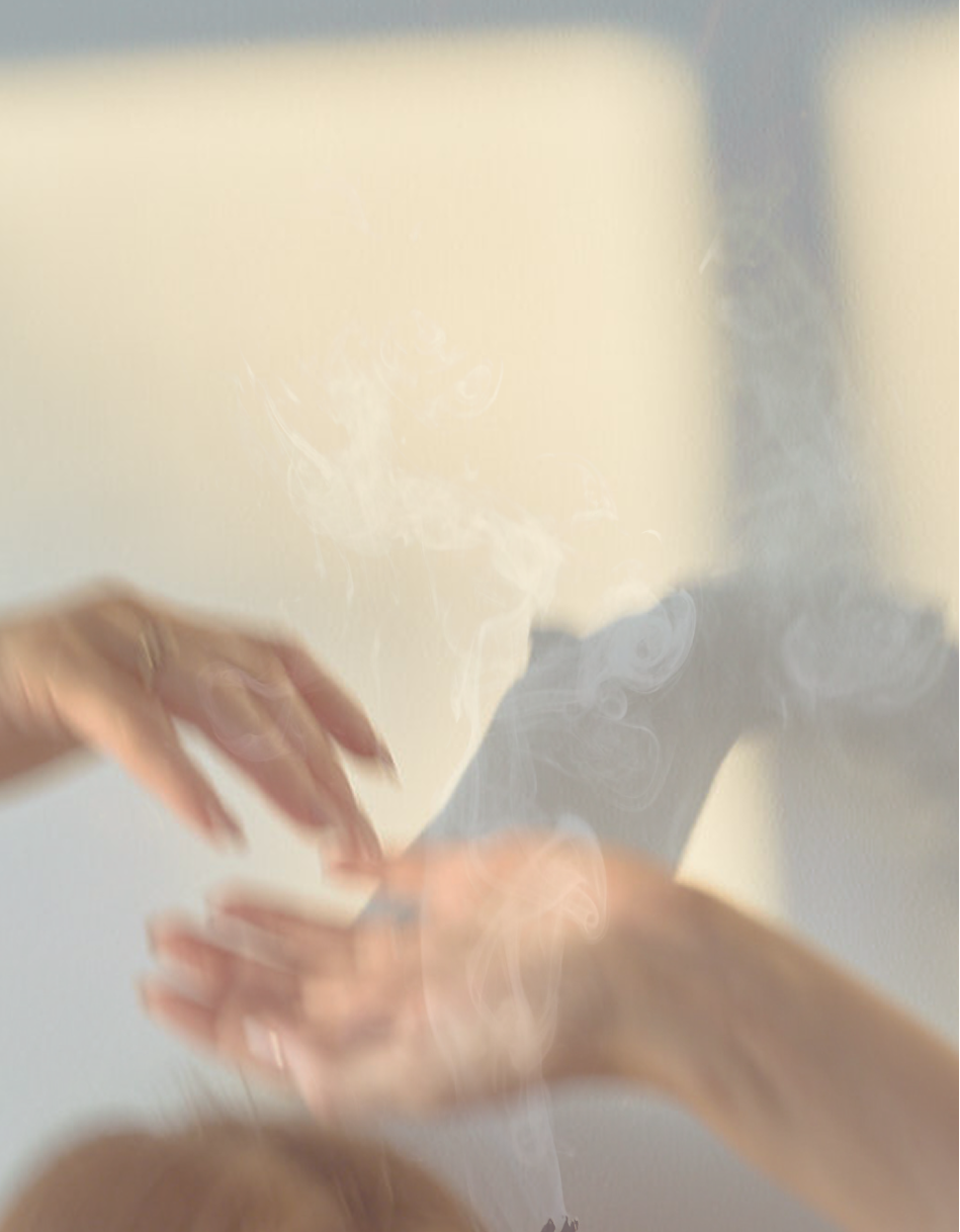 Close-up of two hands with one hand slightly above the other, smoke or vapor rising in between, against a light-colored background.