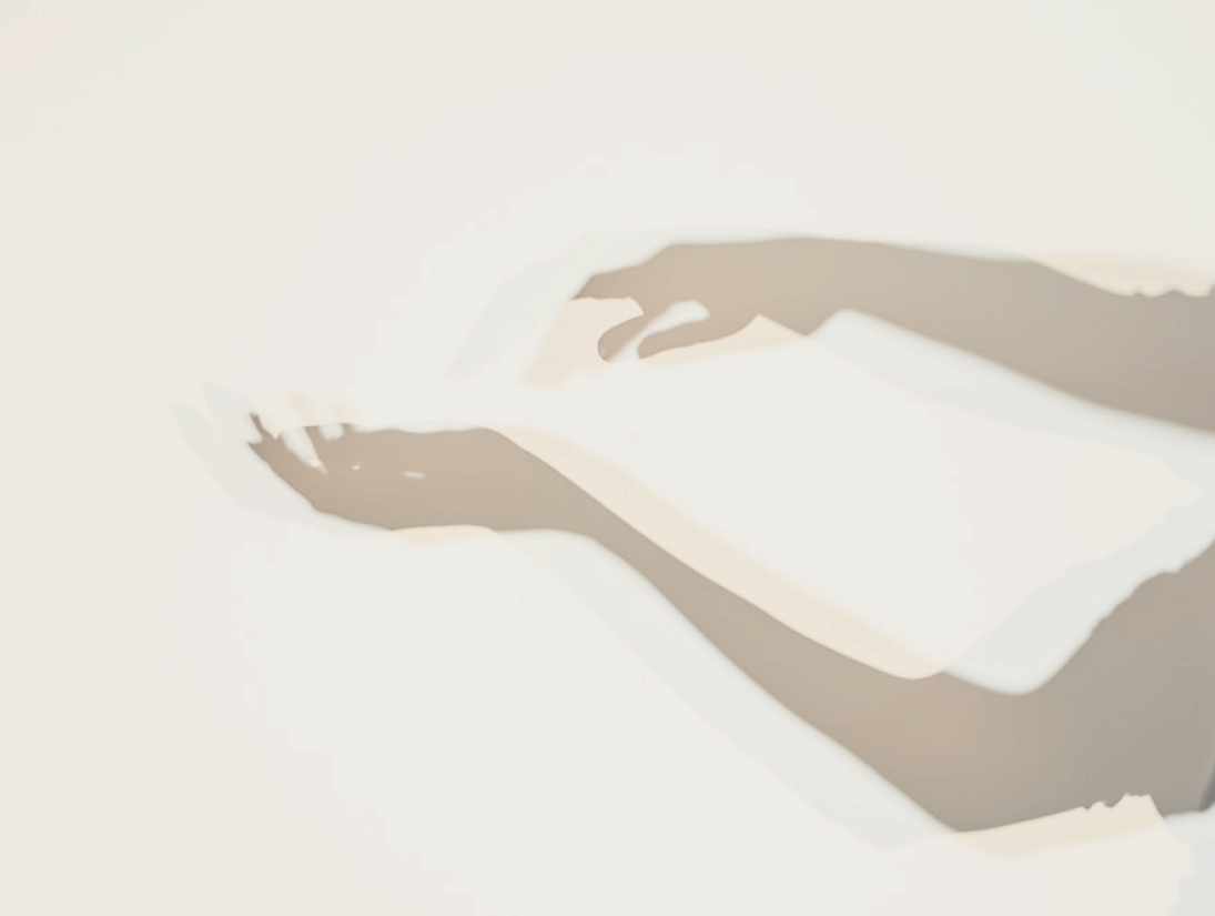 Shadow of a person’s hands holding a smartphone on a white surface.