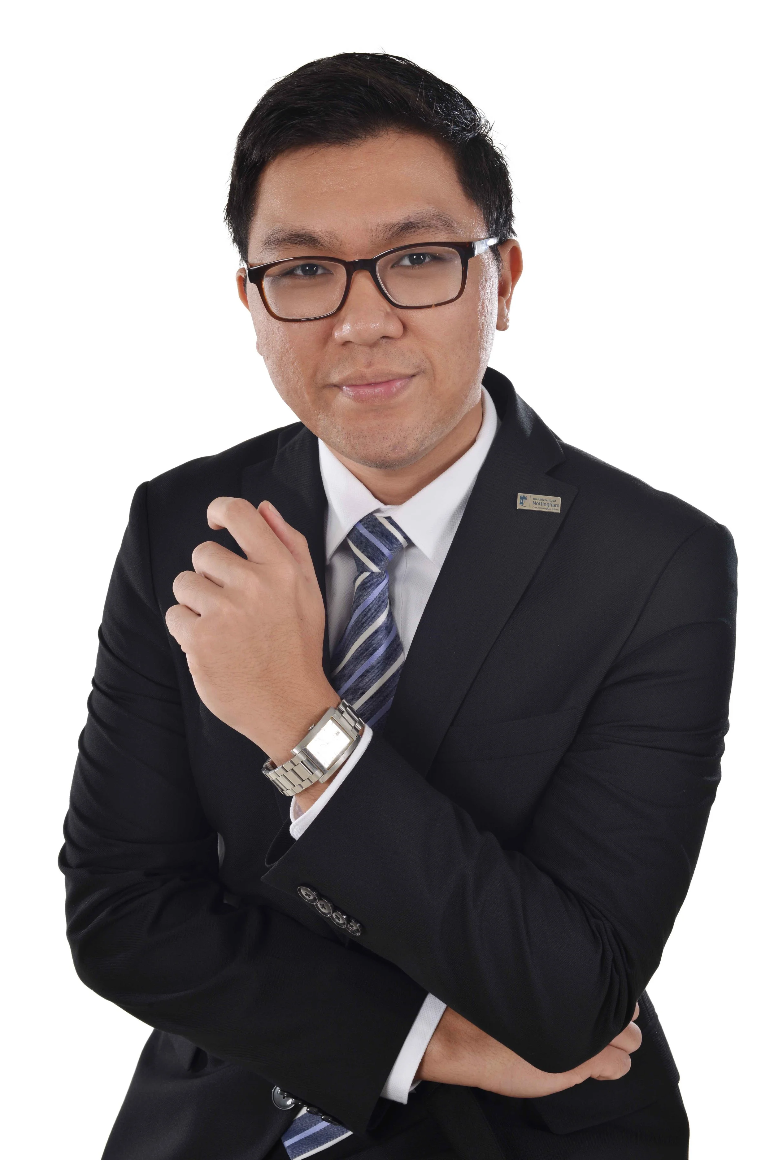 A professional man wearing glasses, a black suit, white shirt, and a striped blue tie, with a watch on his left wrist, standing against a white background.